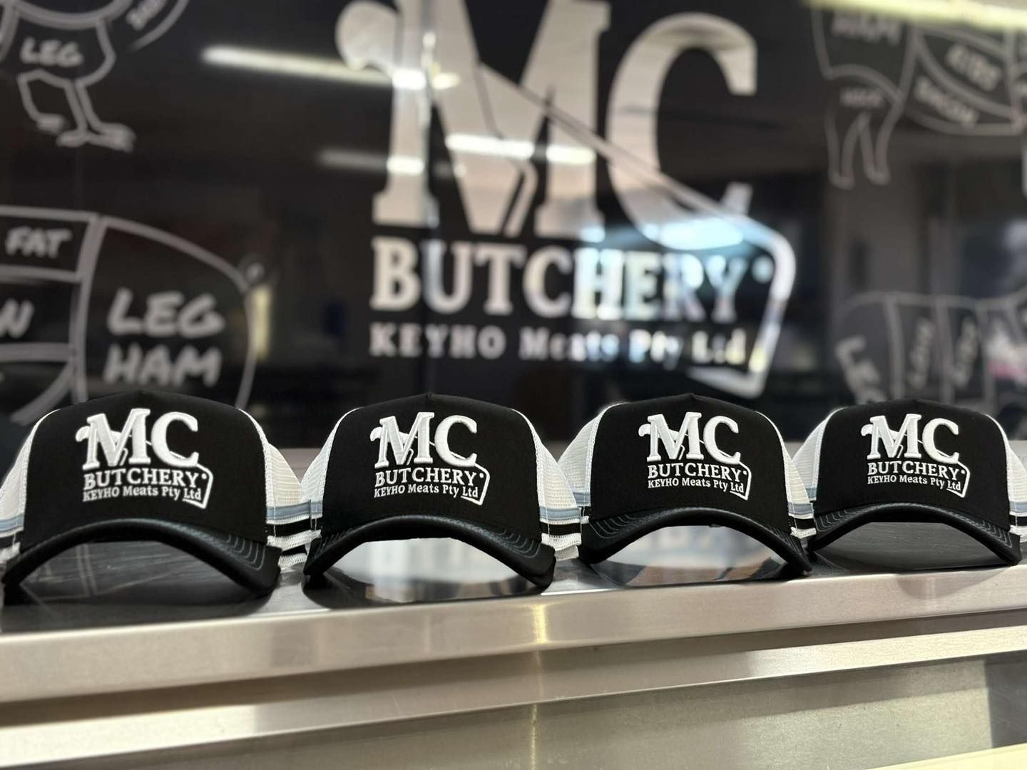 Four mc butchery hats are lined up on a shelf — MC Butchery in Moranbah, QLD