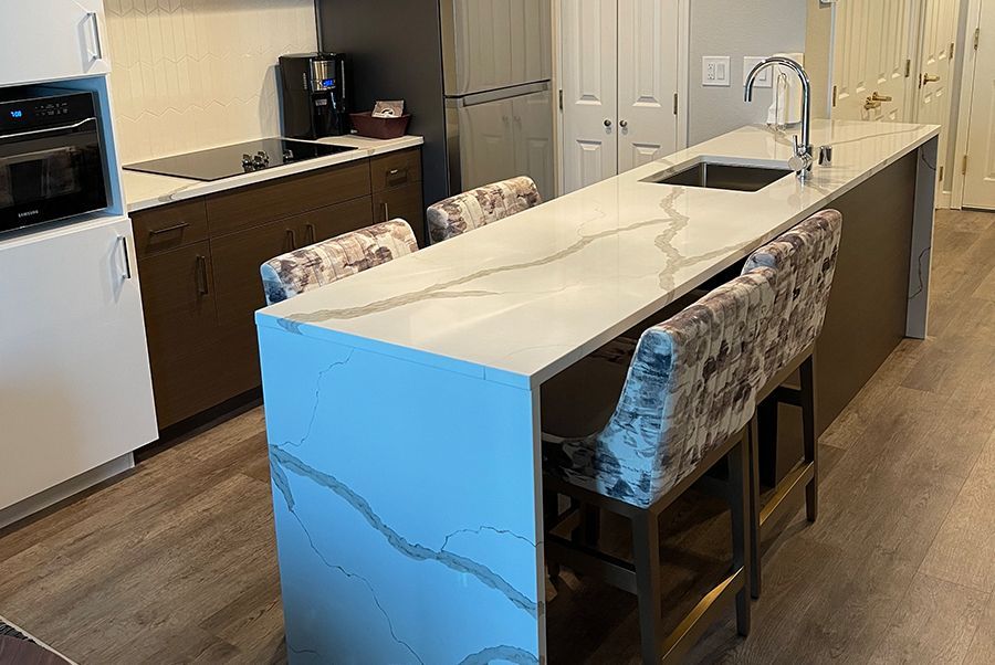 A kitchen with a large island , sink , and chairs.