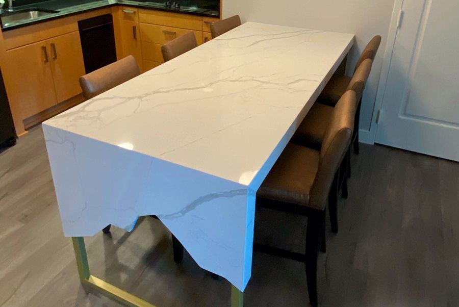 A kitchen with a long white table and chairs