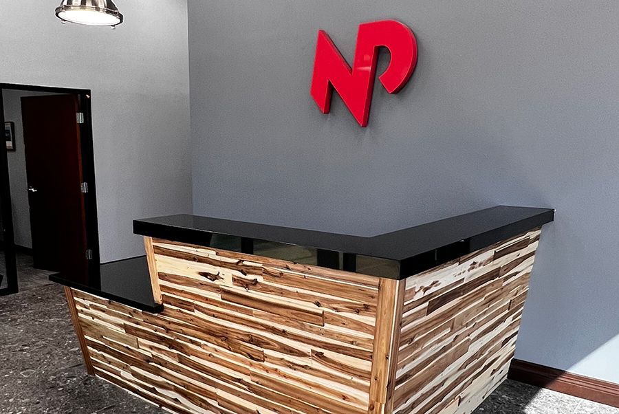 A wooden reception desk with a red np logo on the wall.