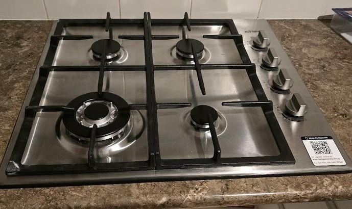A Gas Cylinder Is Sitting On The Side Of A Brick Building Next To A Fence — Country 2 Coast Plumbing And Gas In Wauchope, NSW