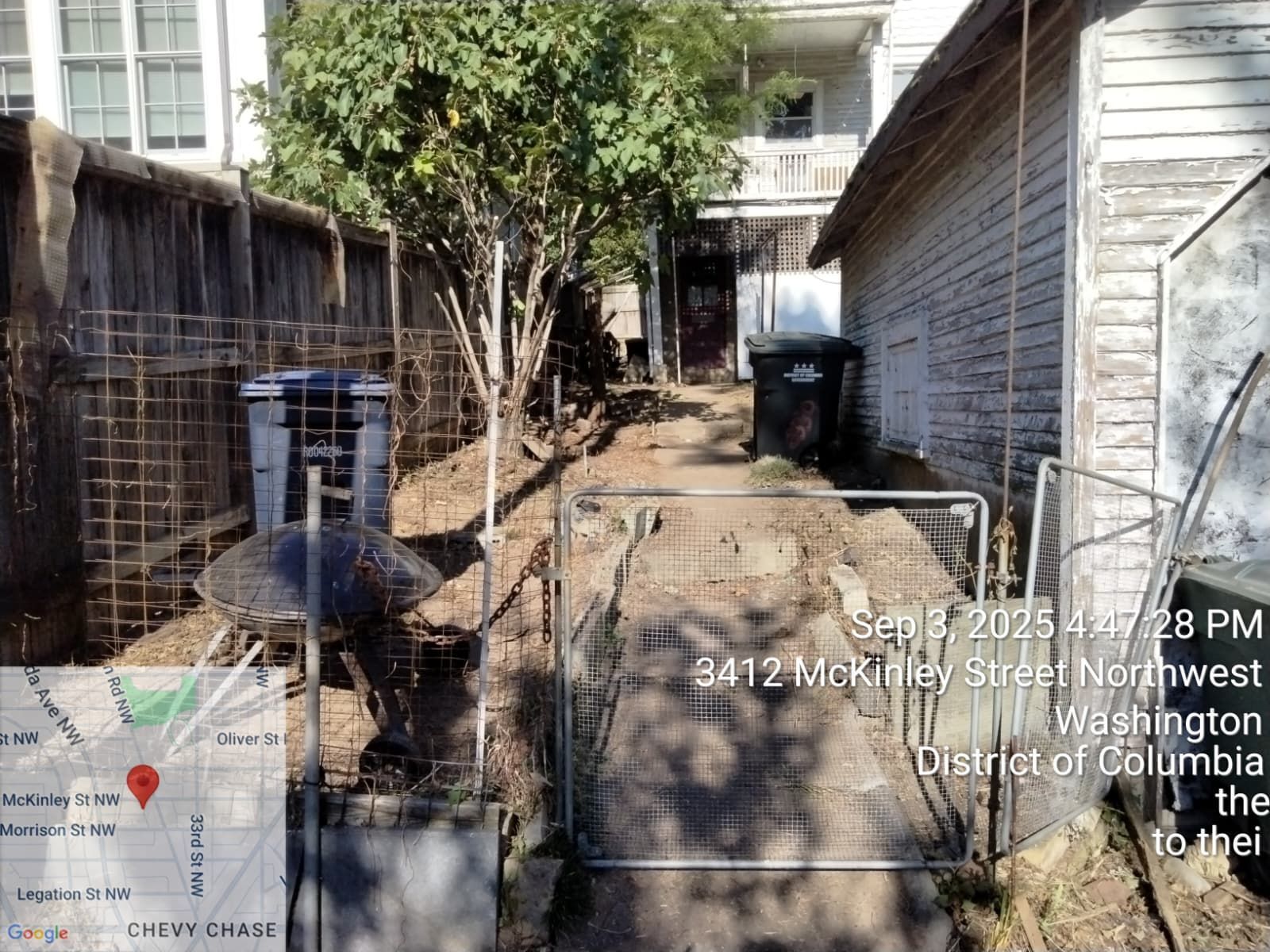 A narrow alley with a fence, trash bins, and a building in Washington, D.C.