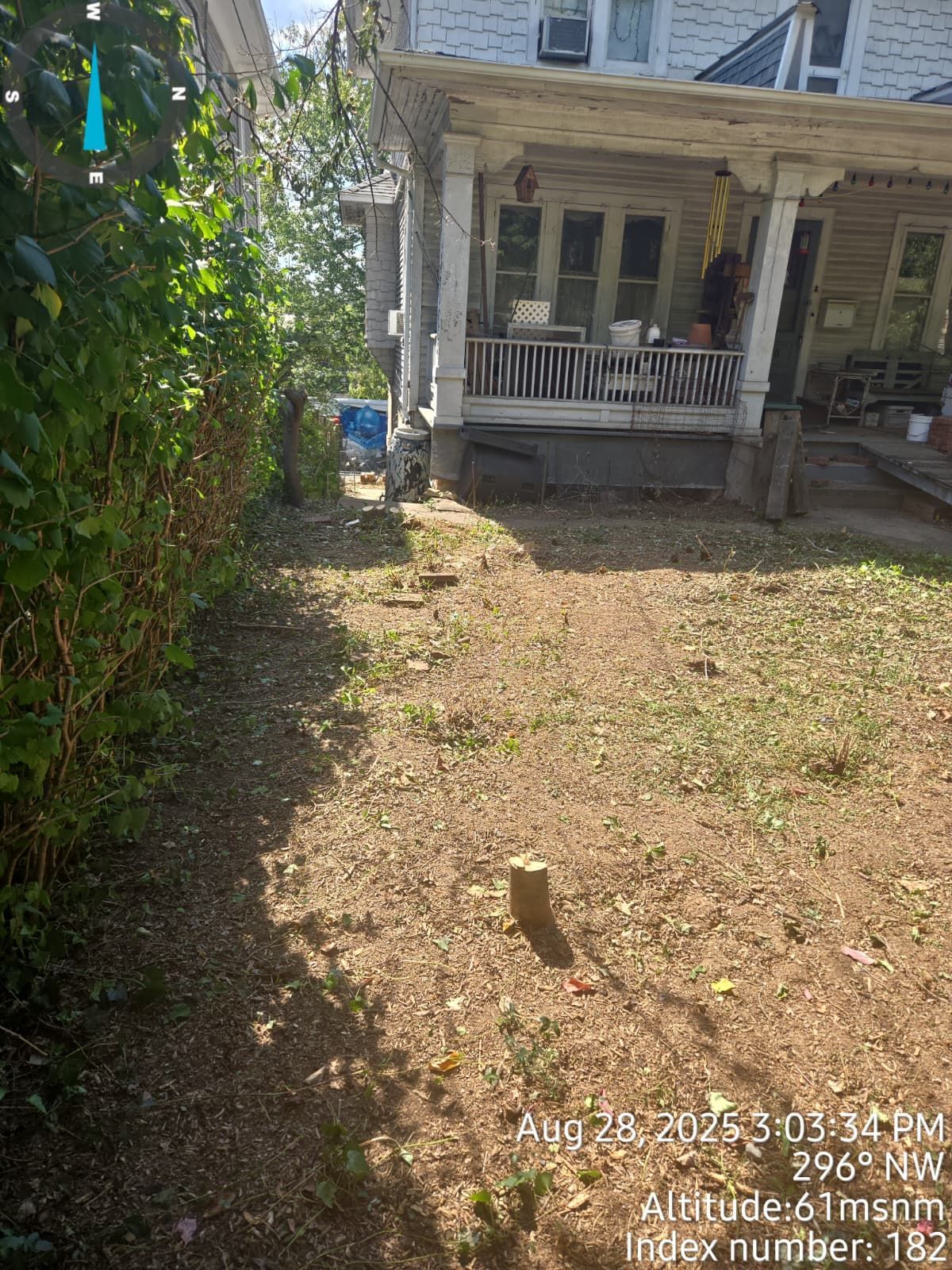 A small, dirt backyard next to a building with a porch.