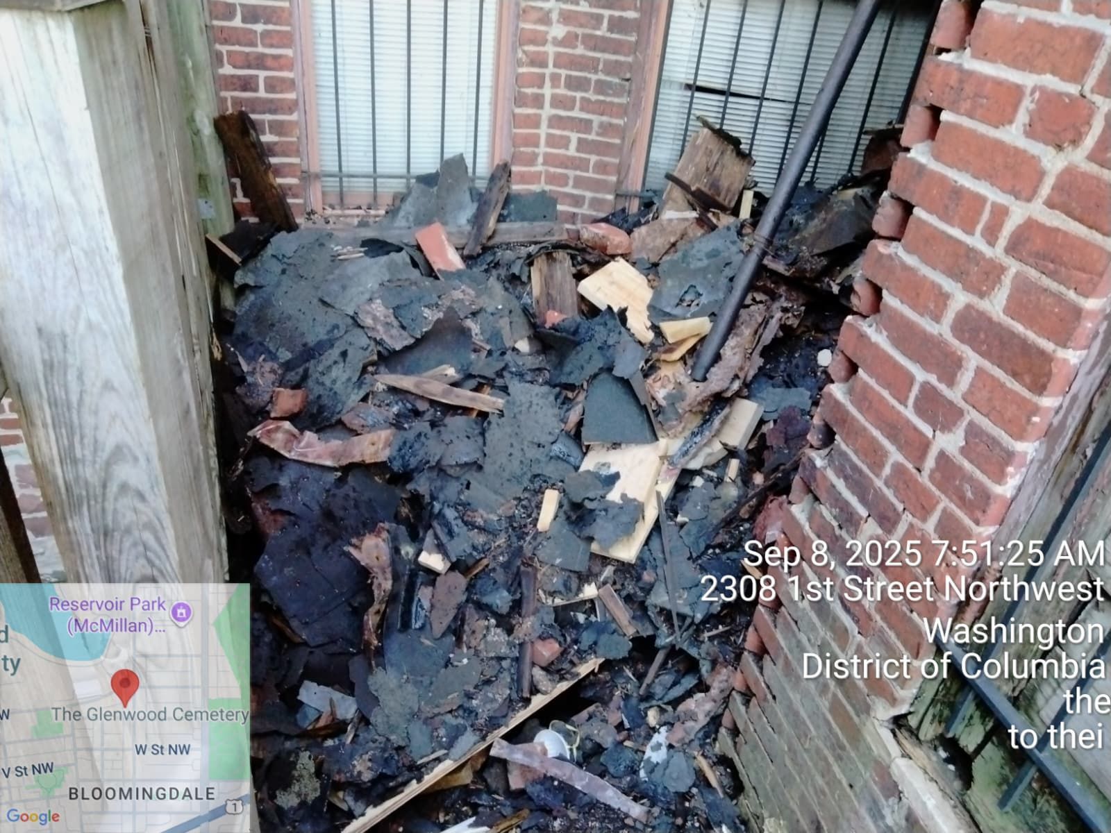 Pile of debris against a brick wall and window, 2308 1st Street NW, Washington DC. Dark colors.