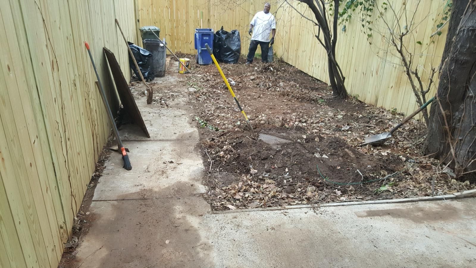 A man is standing in the dirt in a backyard.