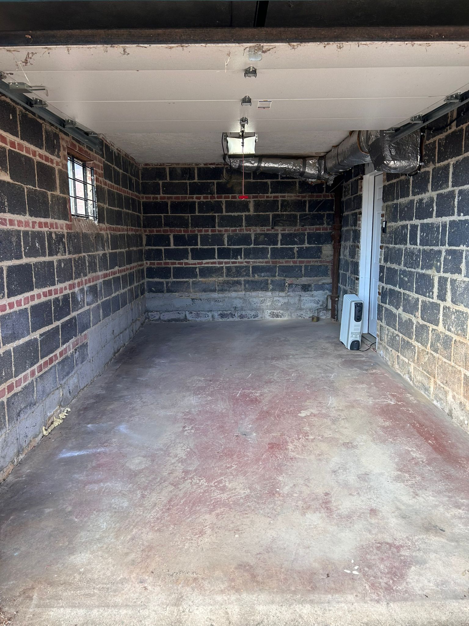 An empty garage with brick walls and a concrete floor.