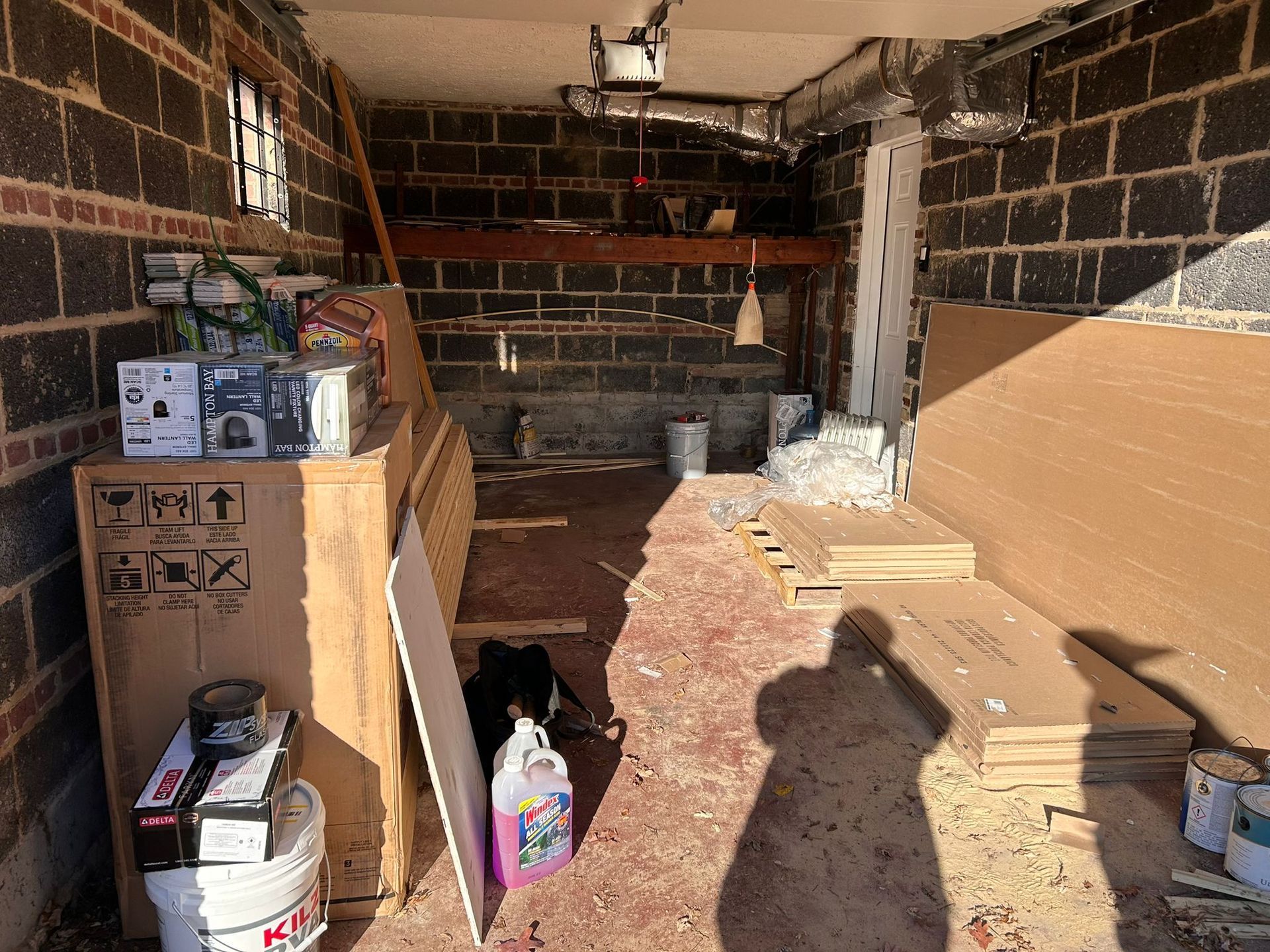 A garage filled with lots of boxes and a bucket of bleach.