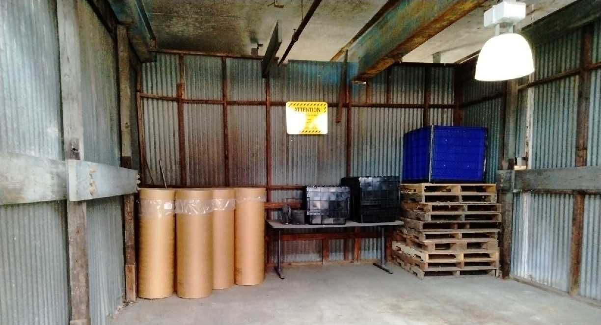 A warehouse with barrels and pallets and a sign that says caution