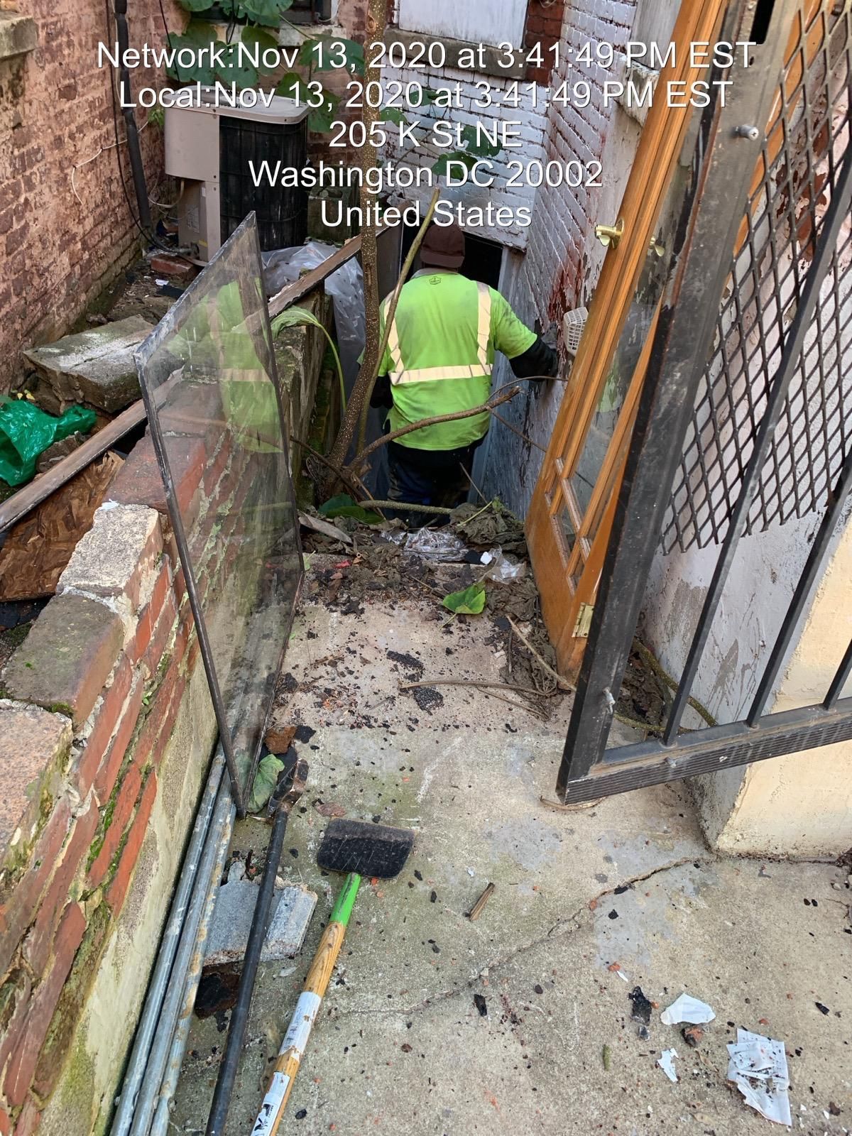 A person in a safety vest working in a cluttered alleyway in Washington, DC.