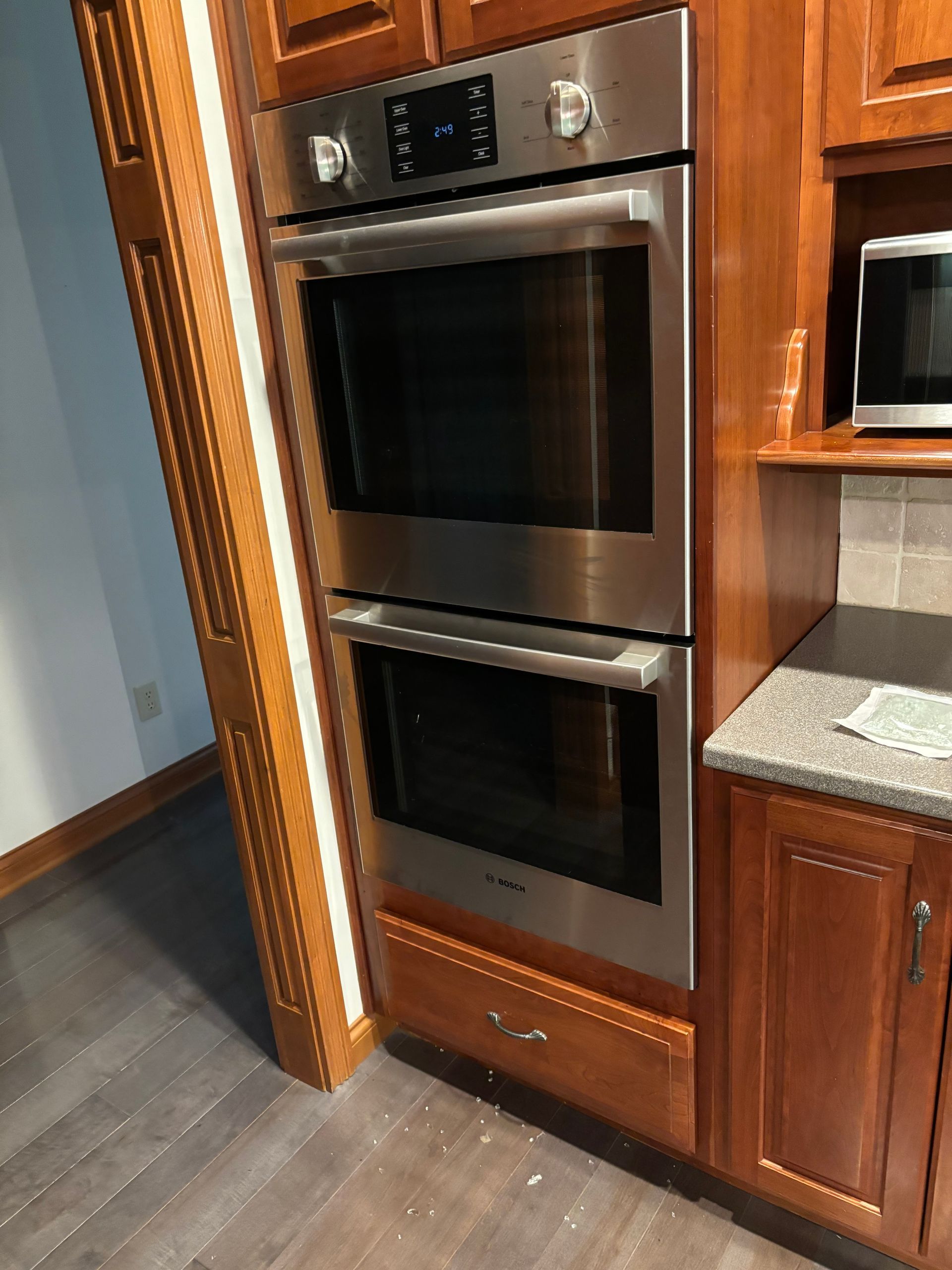 Stainless steel double oven built into wooden cabinetry, kitchen.