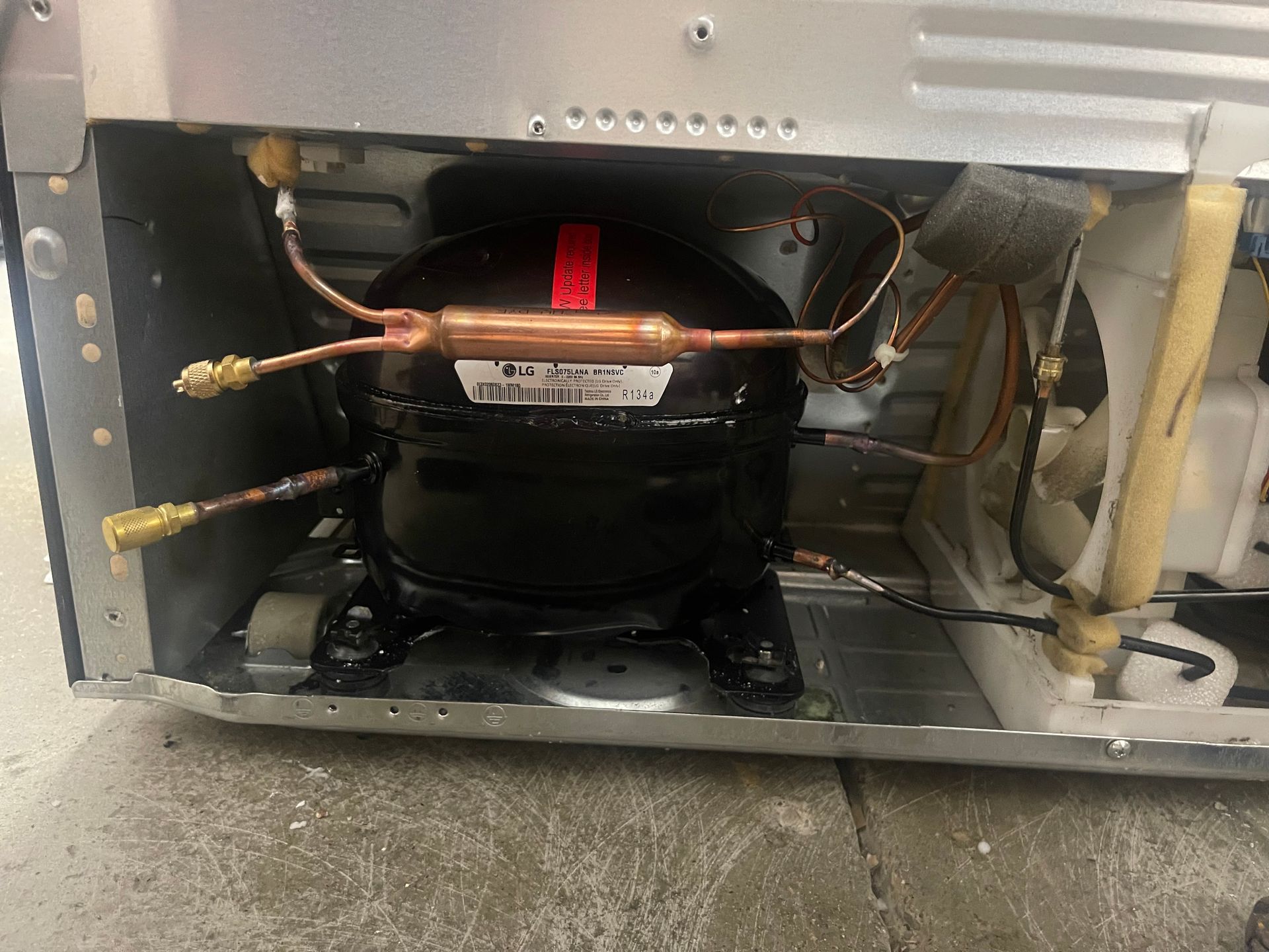 Refrigerator compressor with copper tubing and filter in a metal casing.