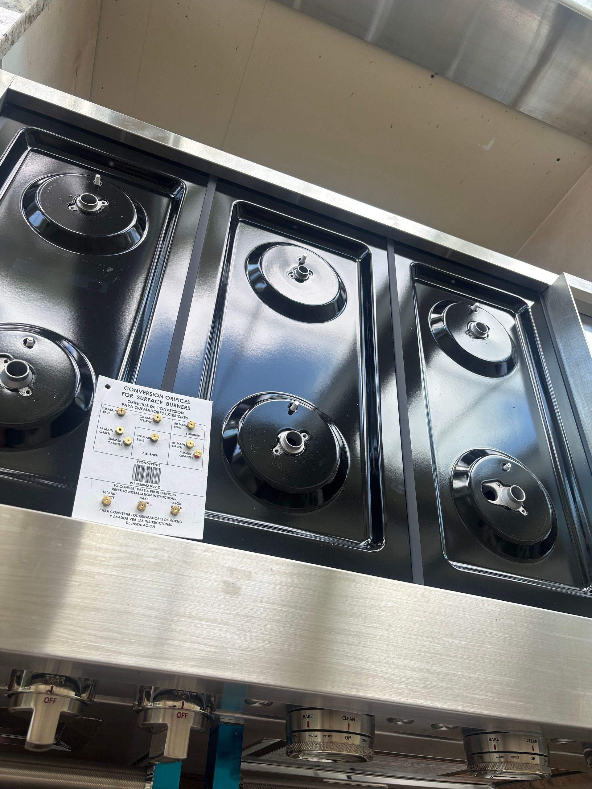 Six-burner gas cooktop with black burners and stainless steel frame. Control knobs are visible at the bottom.