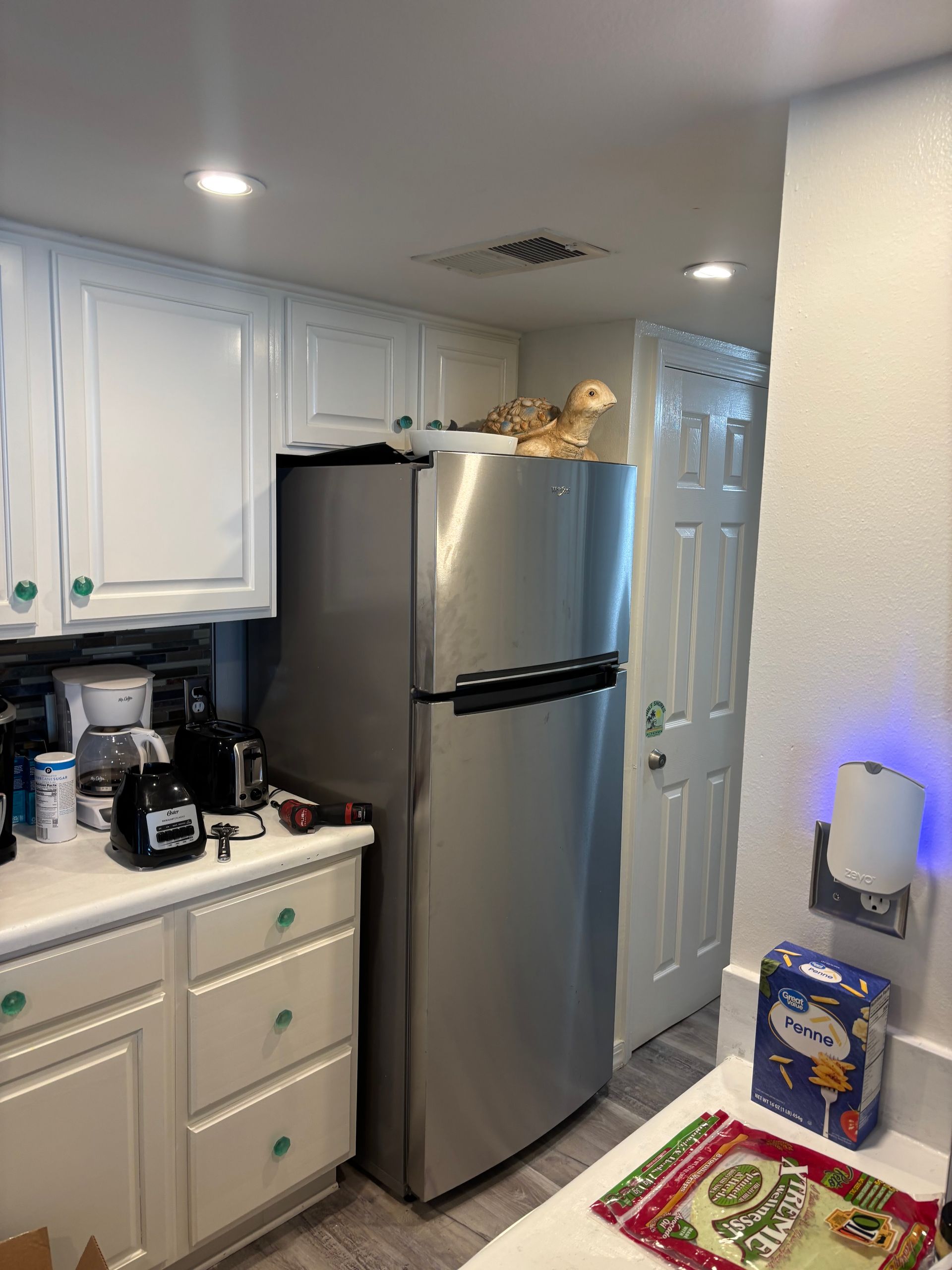 Kitchen with white cabinets, stainless steel fridge, and a ceramic turtle on top.