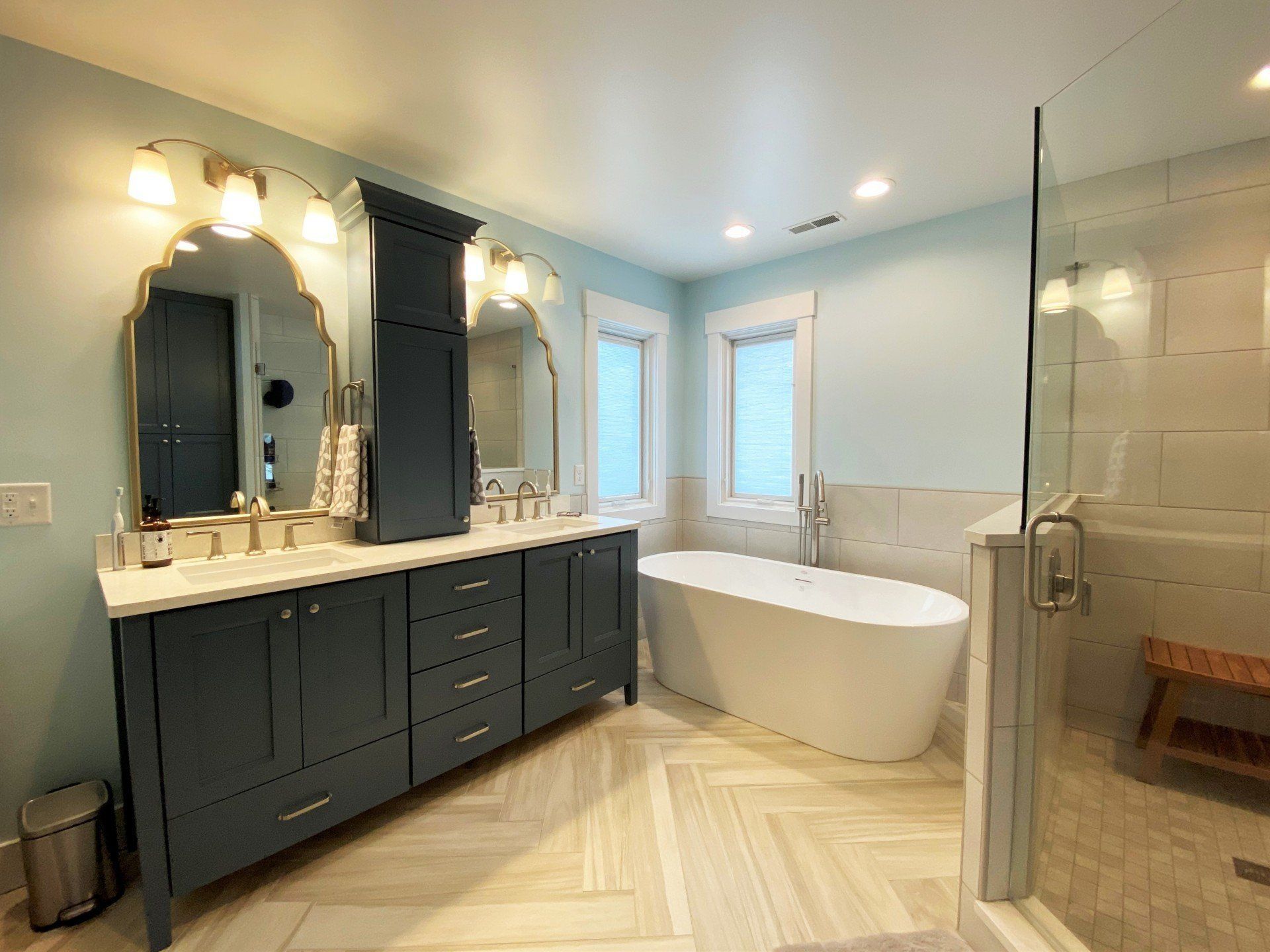 A bathroom with two sinks , a tub , and a walk in shower.