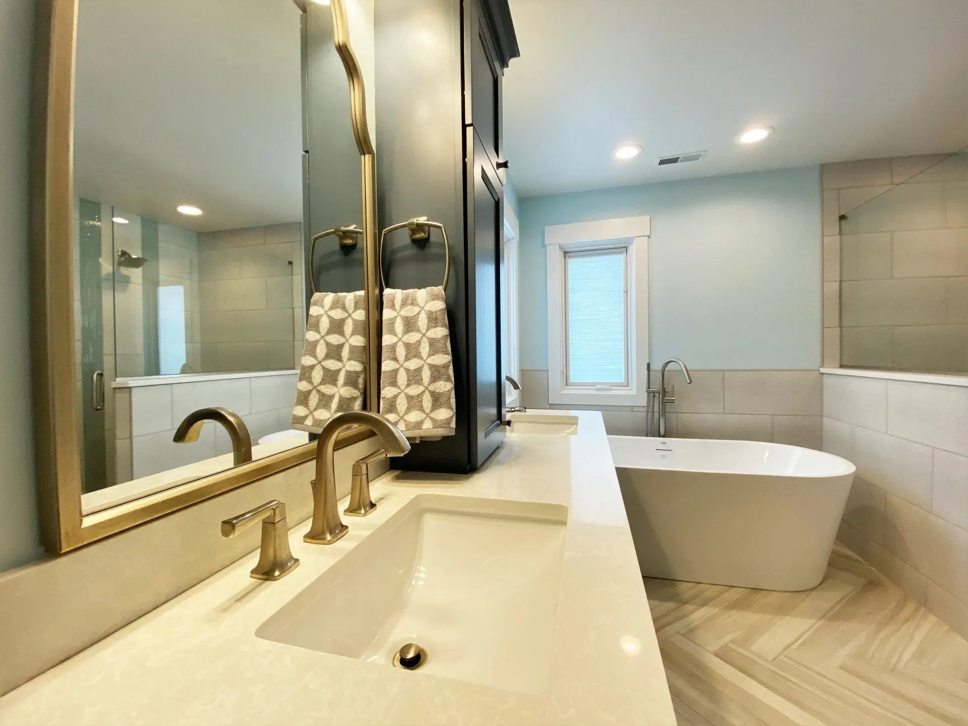 A bathroom with two sinks , a tub and a mirror.