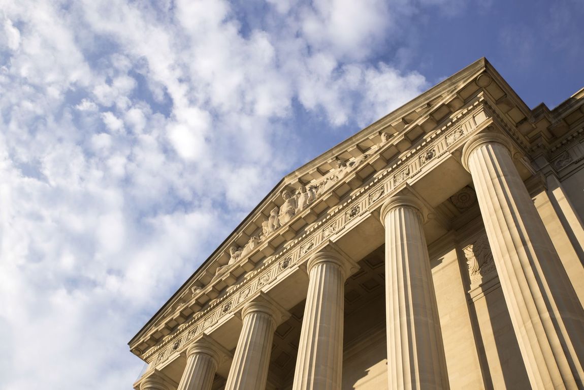 Exterior of a grand, stone building with columns and a decorative roofline