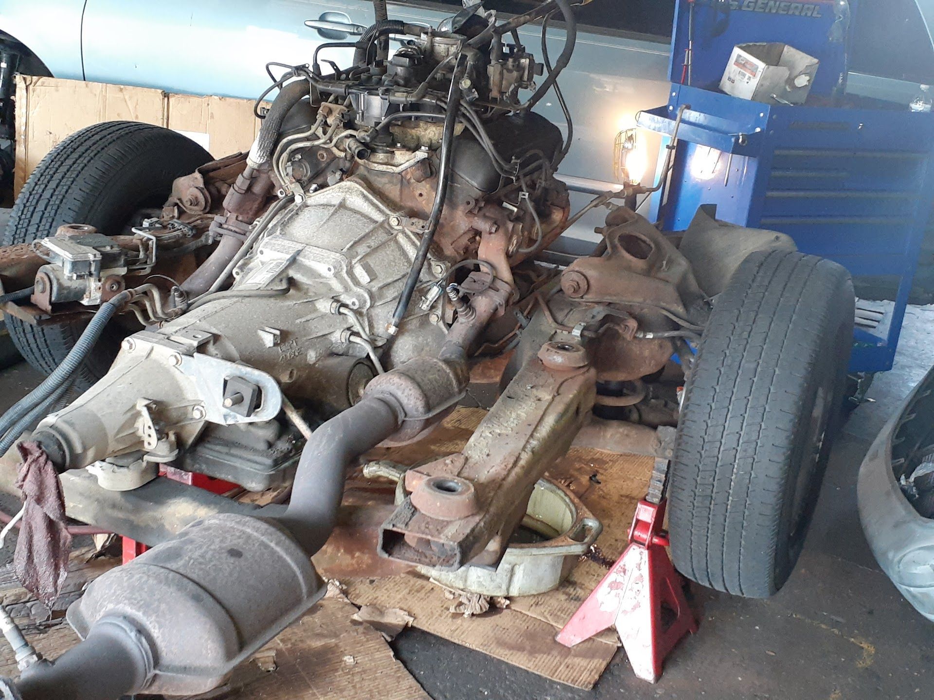 Engine and transmission removed from vehicle chassis in a garage | Action Service Center