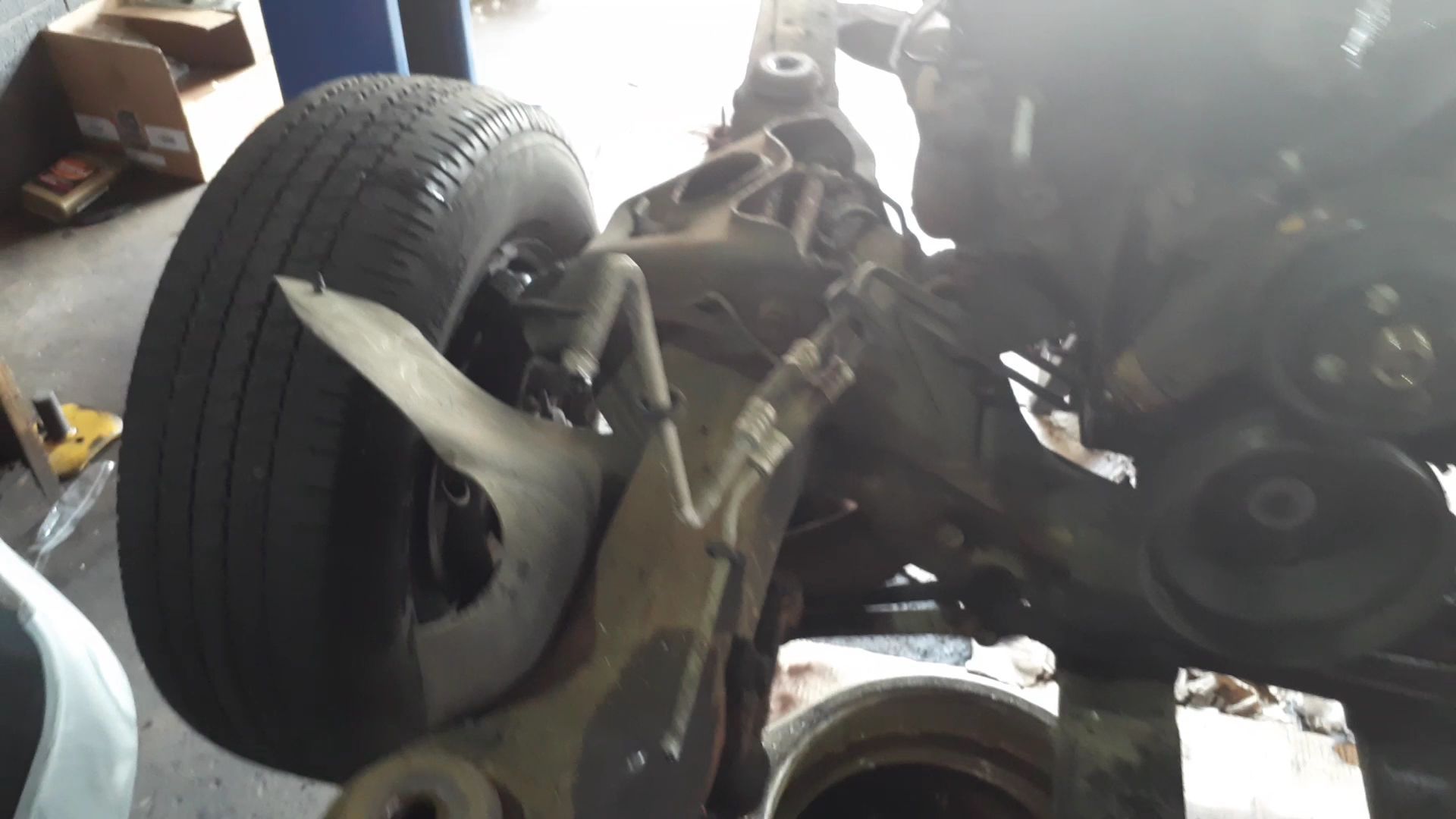 Close-up of a car's undercarriage with a wheel and suspension components, in a garage | Action Service Center