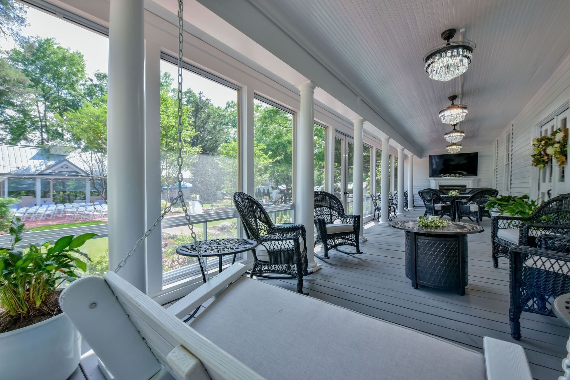 A screened in porch with rocking chairs and a red couch.
