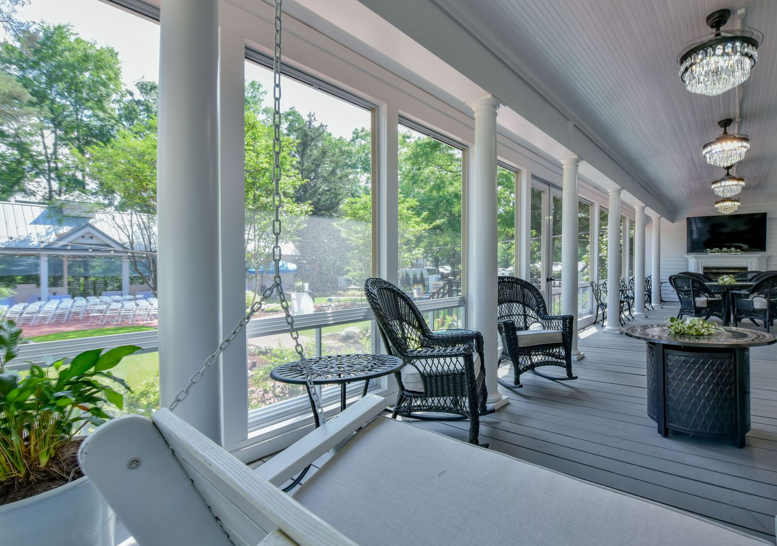 A screened in porch with rocking chairs and a red couch.