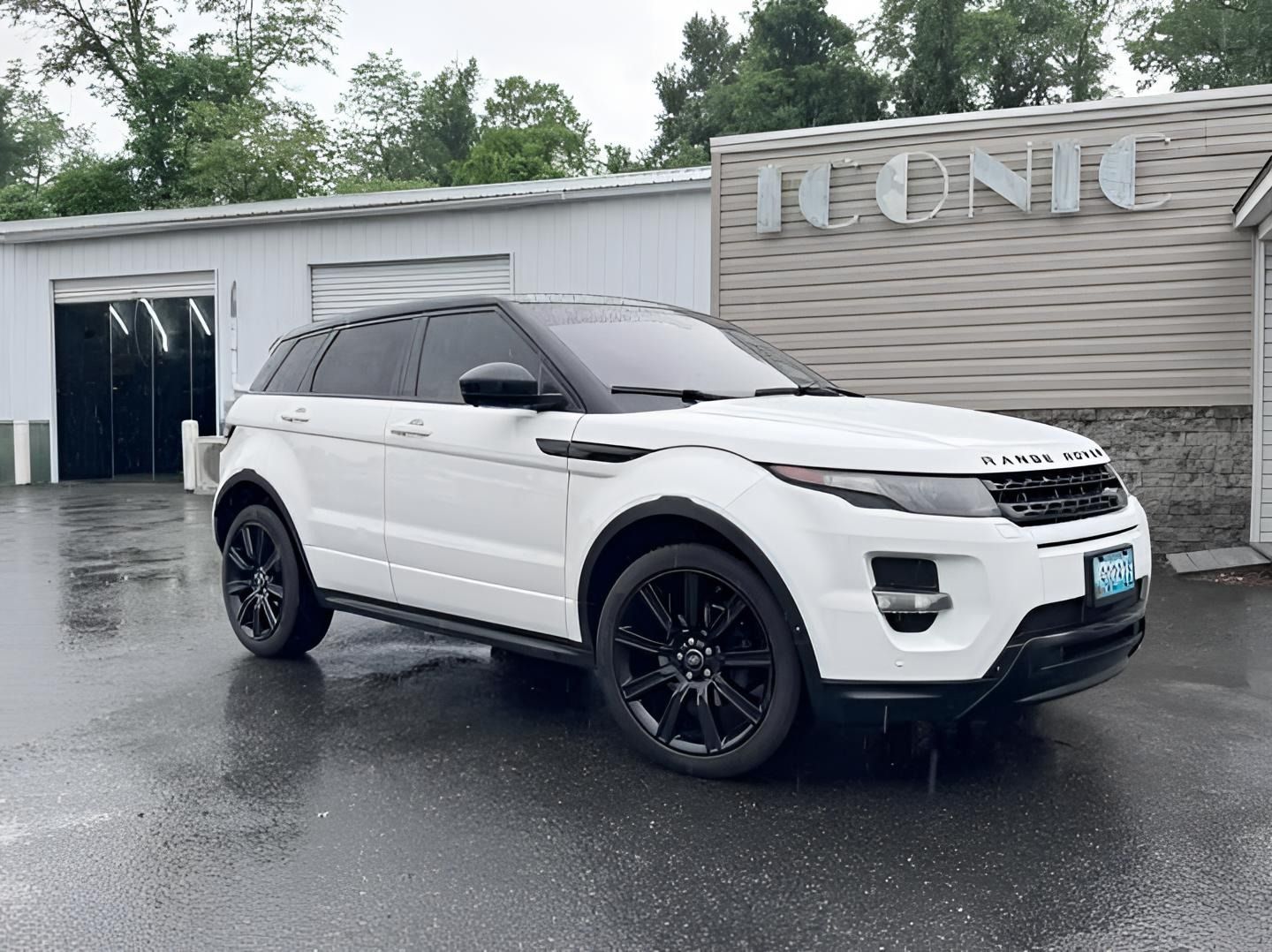 White Range Rover parked in front of a building on a rainy day