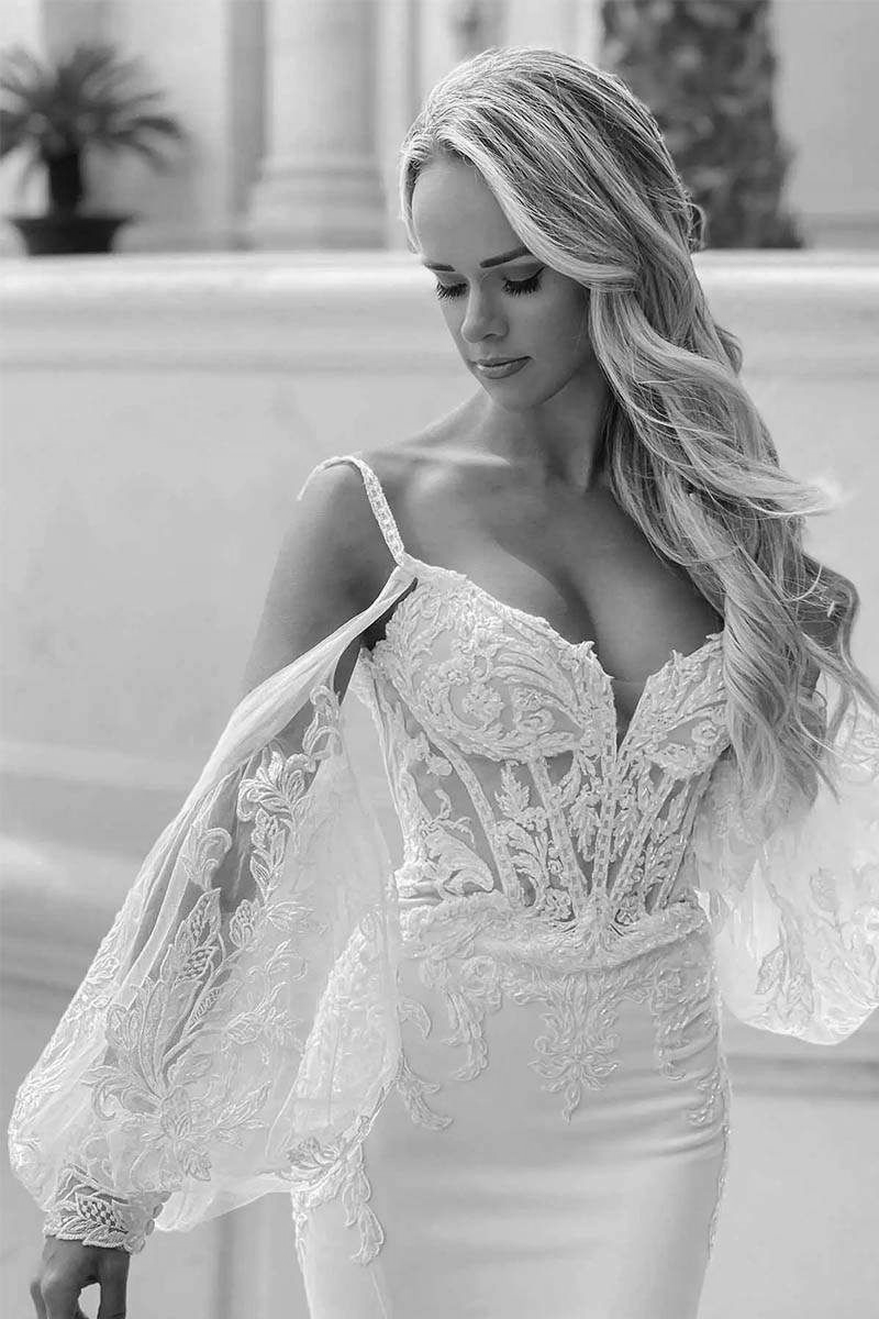 Woman in white lace wedding dress, long blonde hair, looking down, light setting.