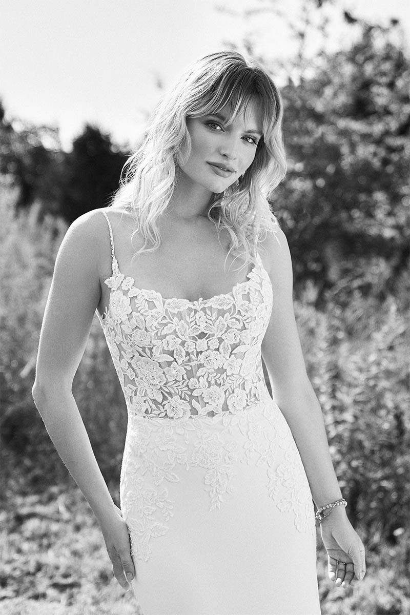 Woman in white wedding dress with floral bodice, outdoor setting.