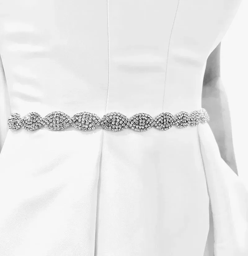 Woman in white dress with sparkly rhinestone belt at waist.