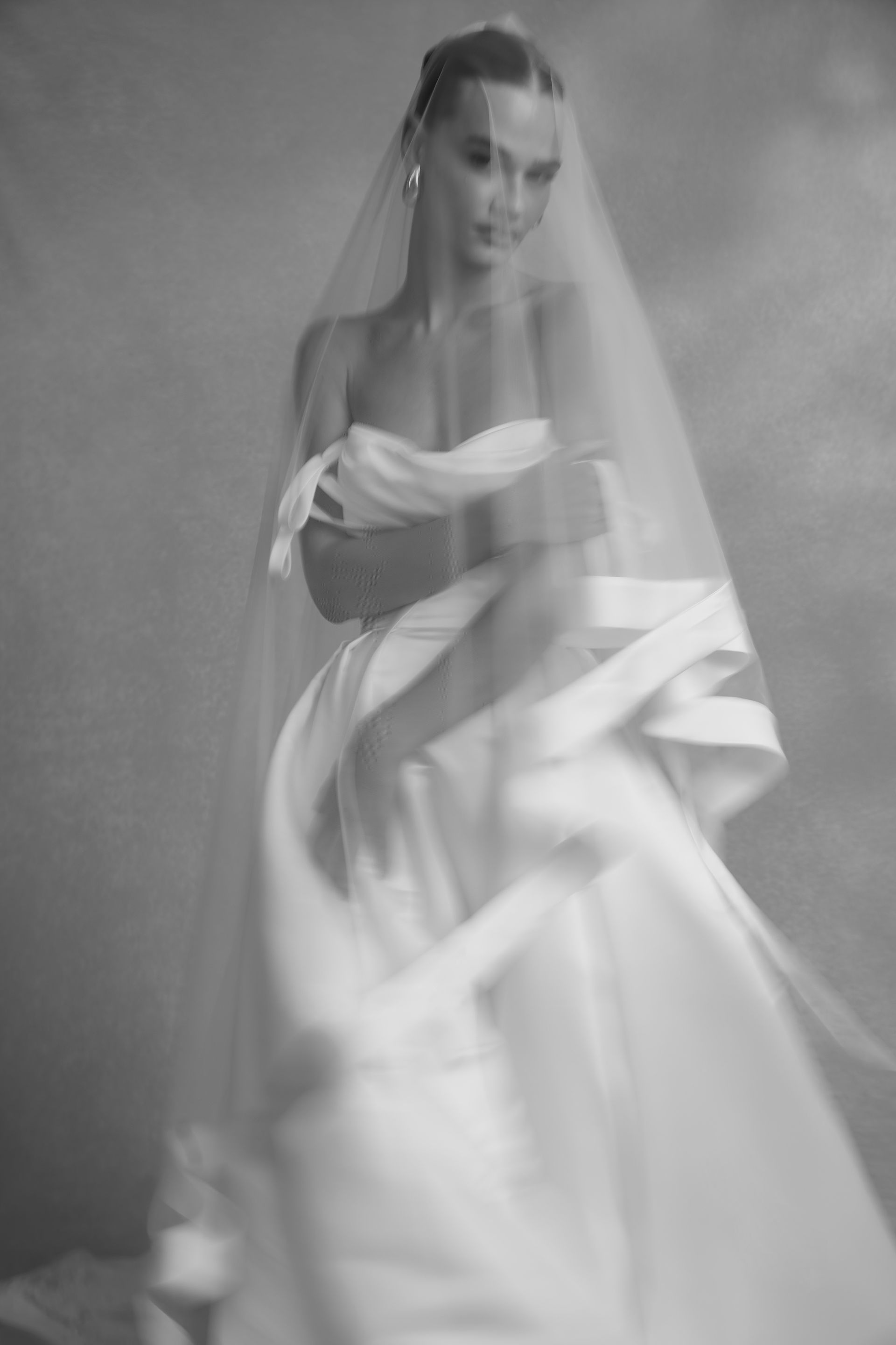 Woman in a lace wedding dress with long sleeves, standing with back to camera.