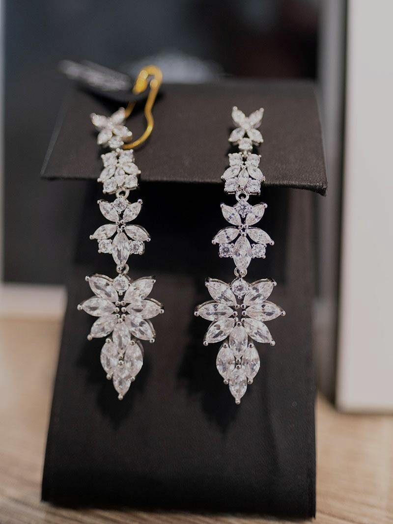 Elegant, silver drop earrings with multiple clear, sparkling crystal flower-shaped clusters.