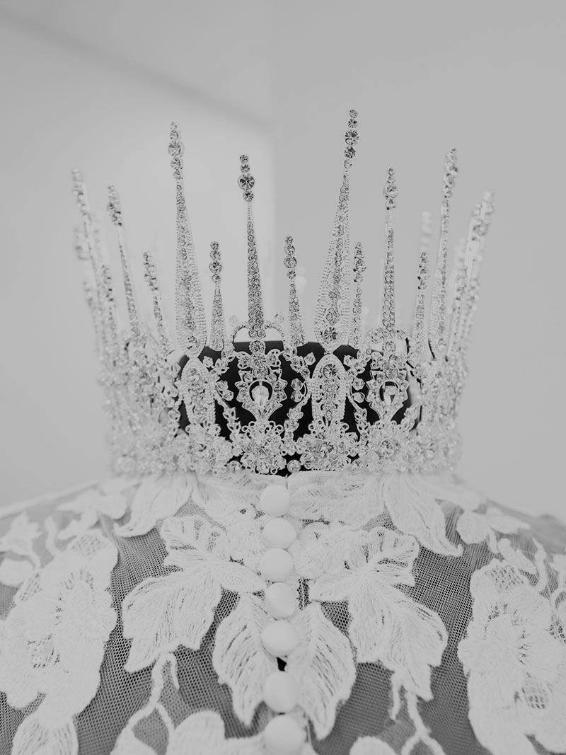 Crown on a lacy white dress, close up. Silver tiara with tall spires, black and white.