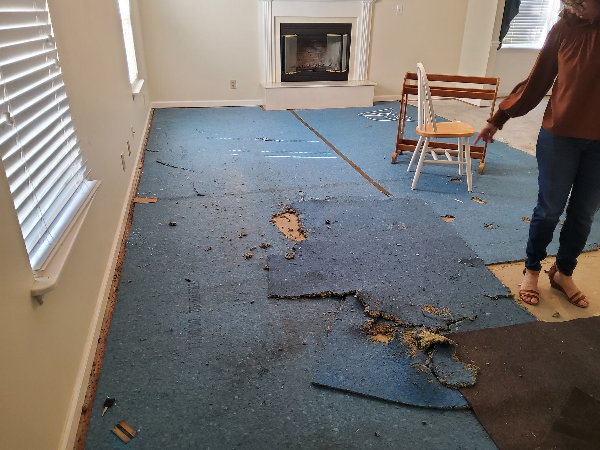 A woman is standing in a living room with a blue carpet on the floor.