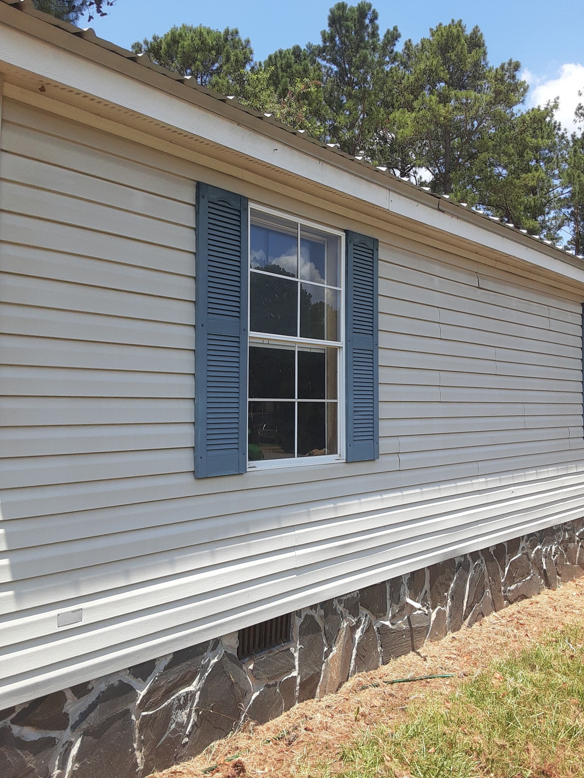 A white mobile home with blue shutters on the windows