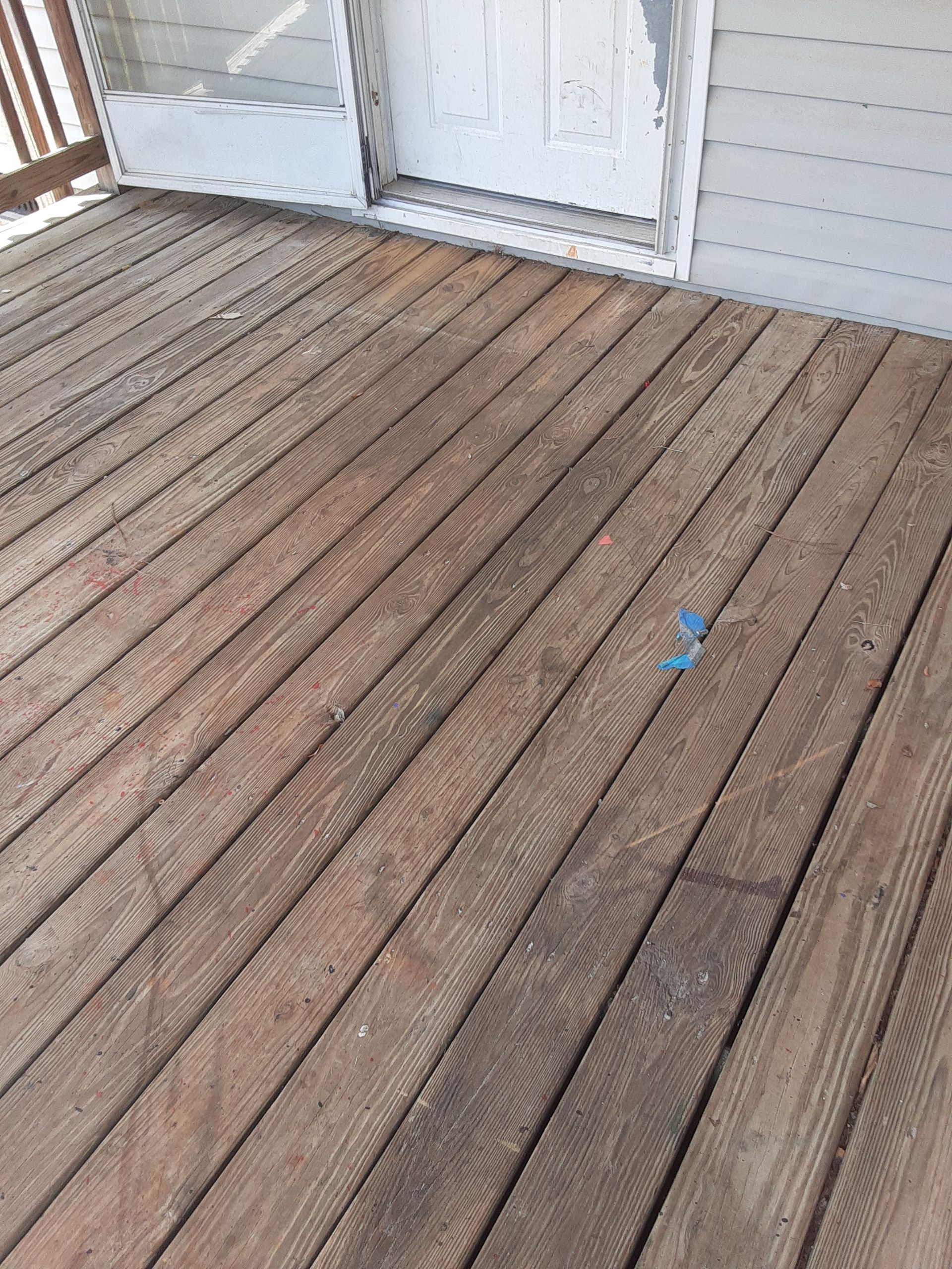 A wooden deck with a white door in the background.
