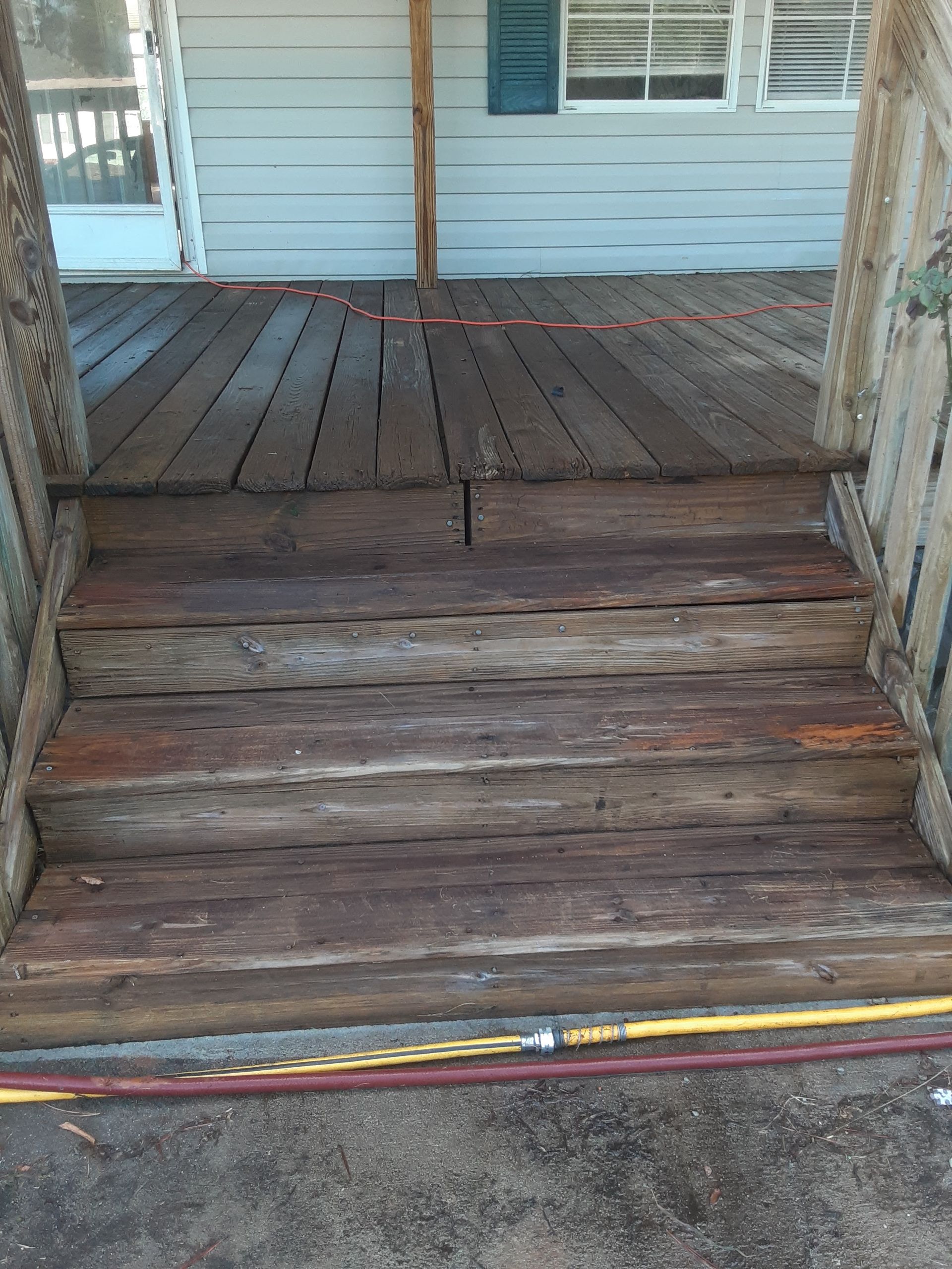 A wooden deck with stairs leading up to a house.