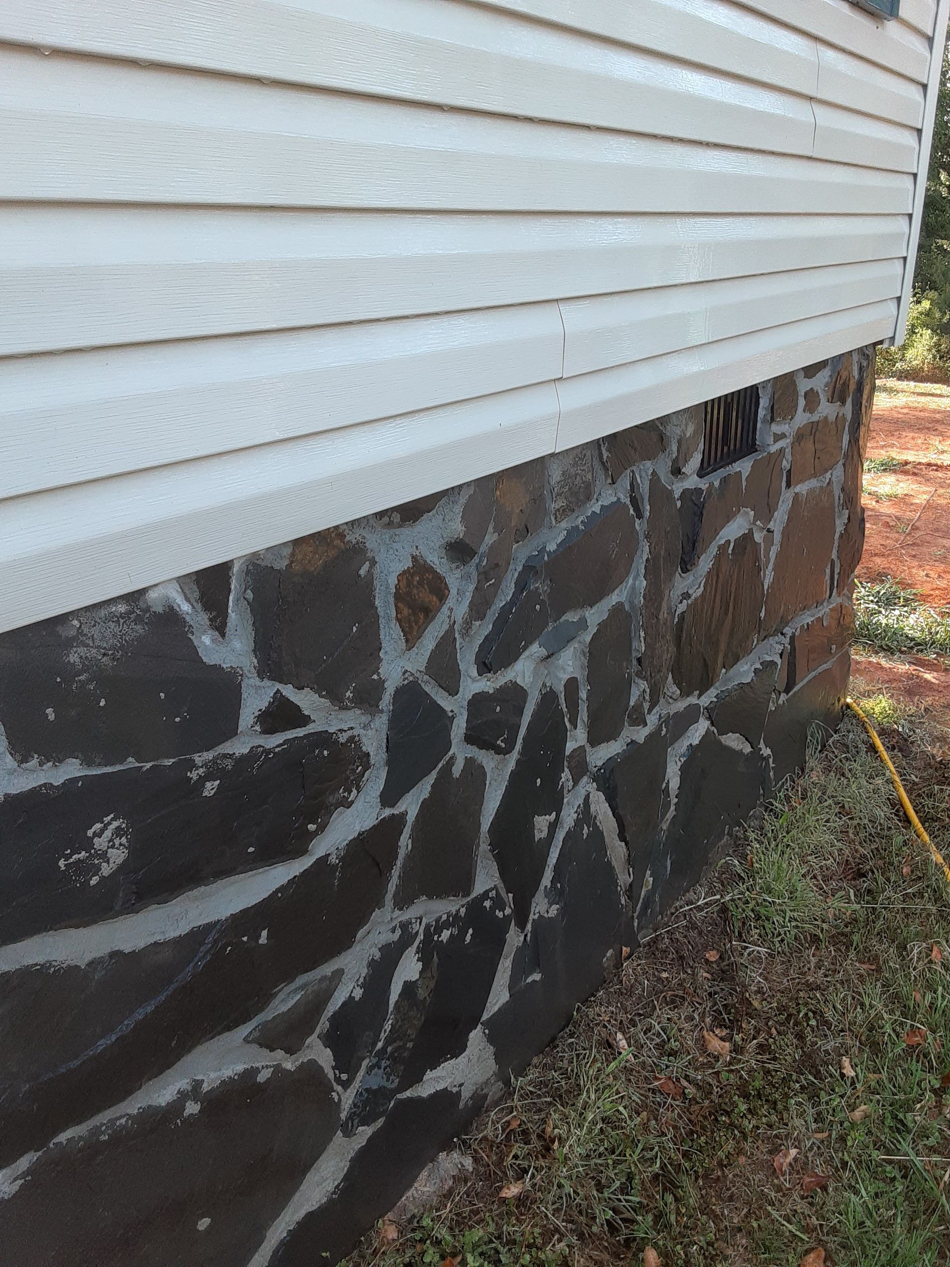 A house with a stone foundation and a white siding