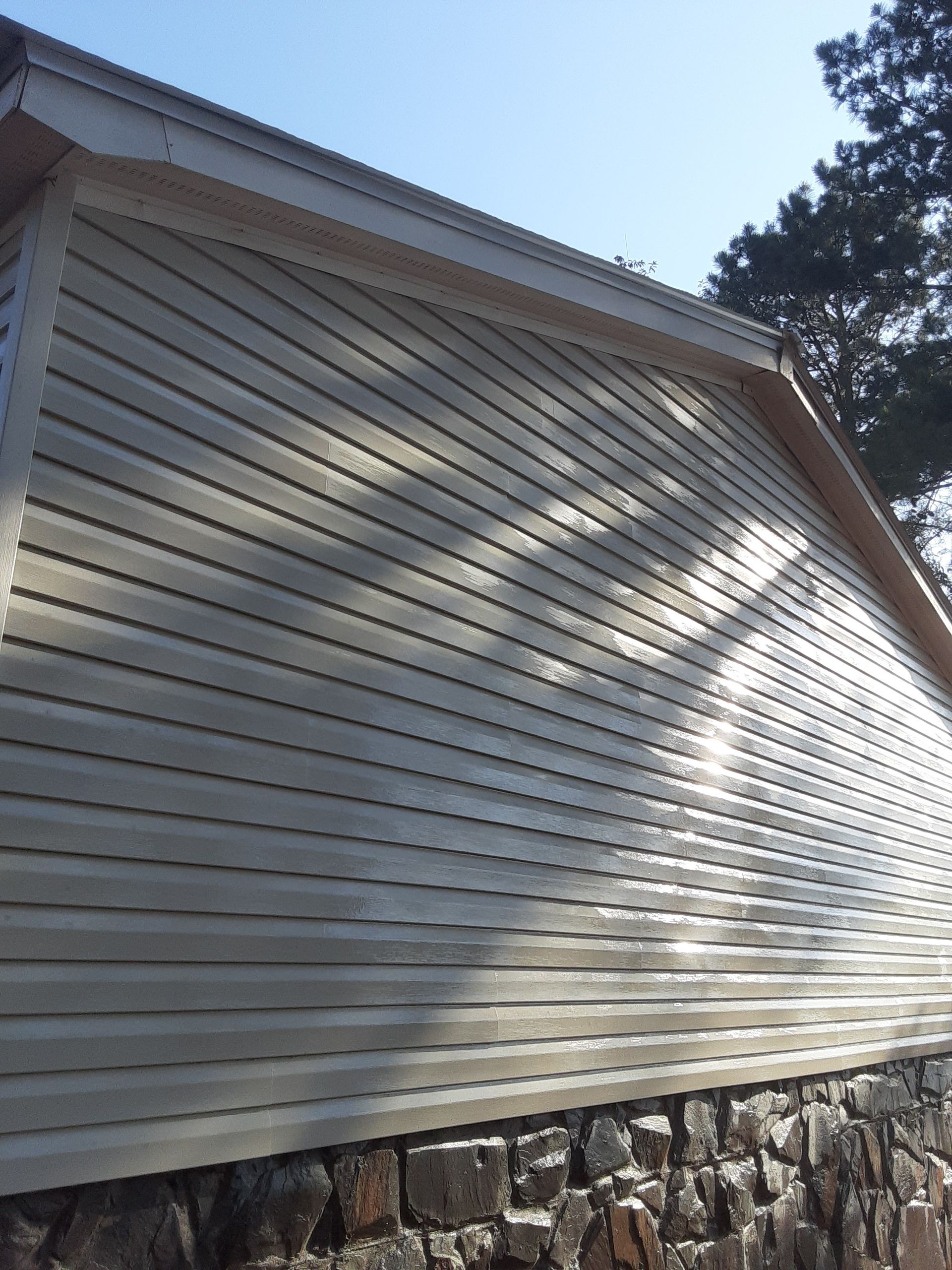 A white house with a stone wall and a blue sky in the background.