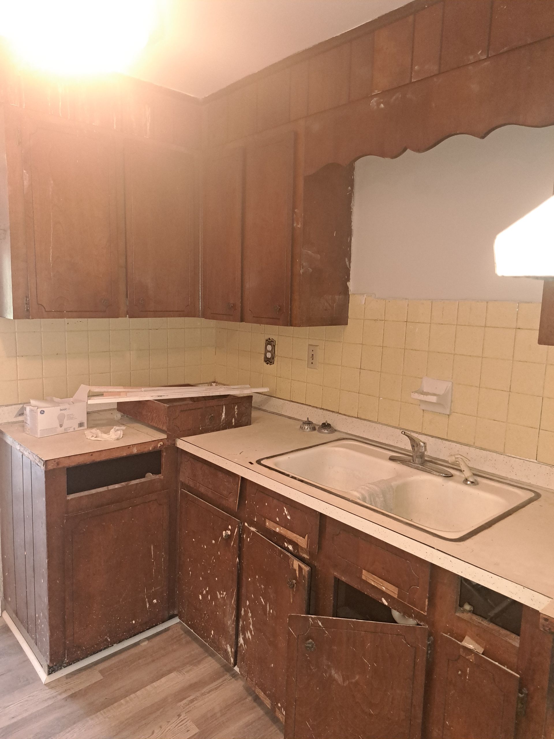 A kitchen with wooden cabinets , a sink , and a stove.