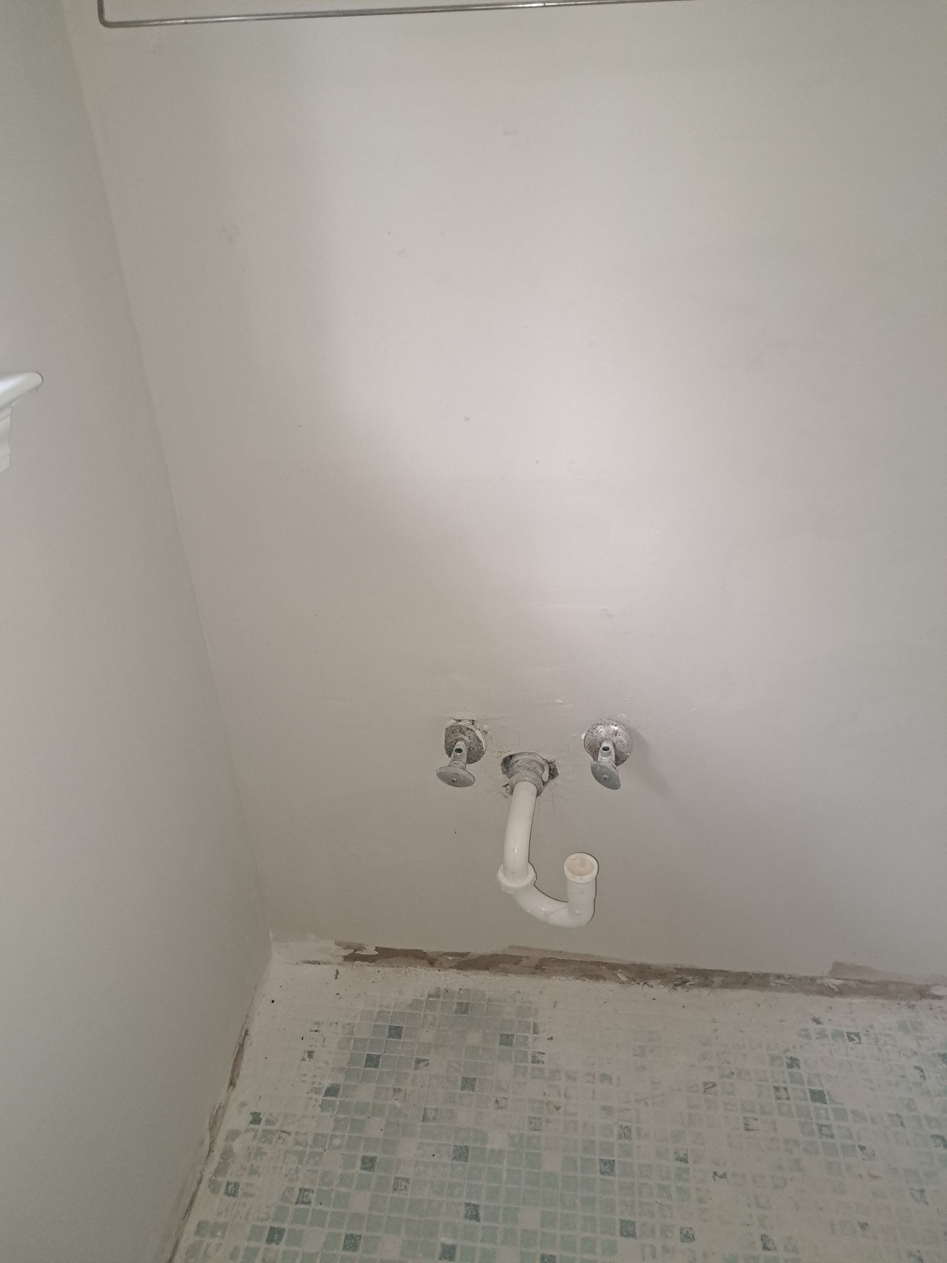 A bathroom with a sink and faucets on the wall.