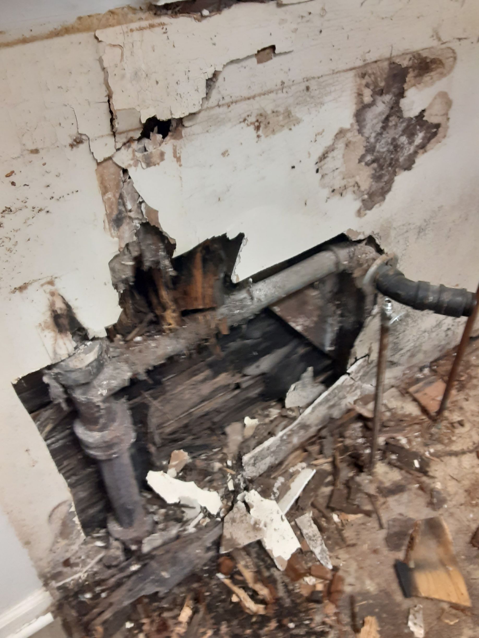 A hole in a wall with pipes coming out of it