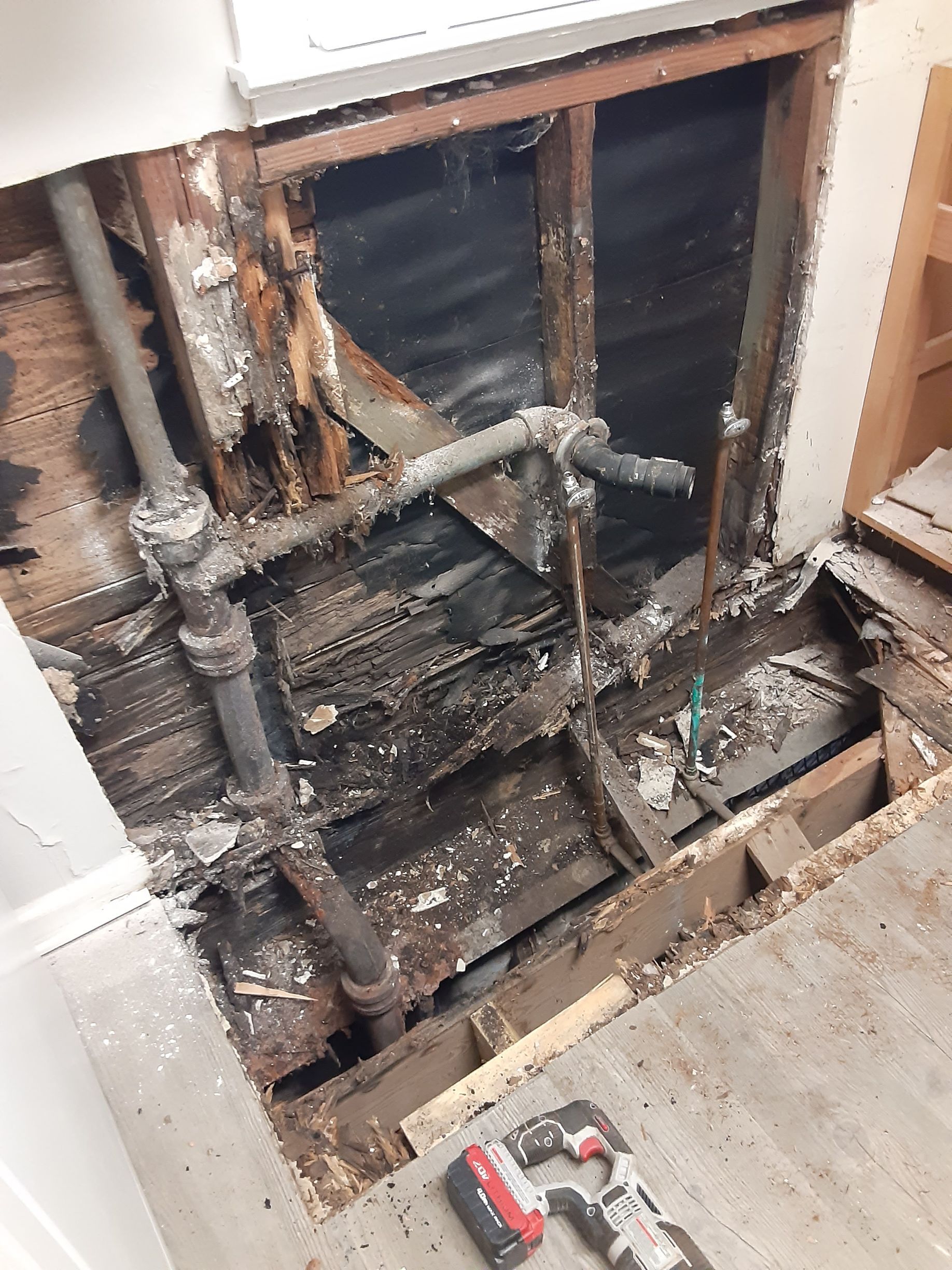 A hole in the floor of a building with pipes coming out of it.