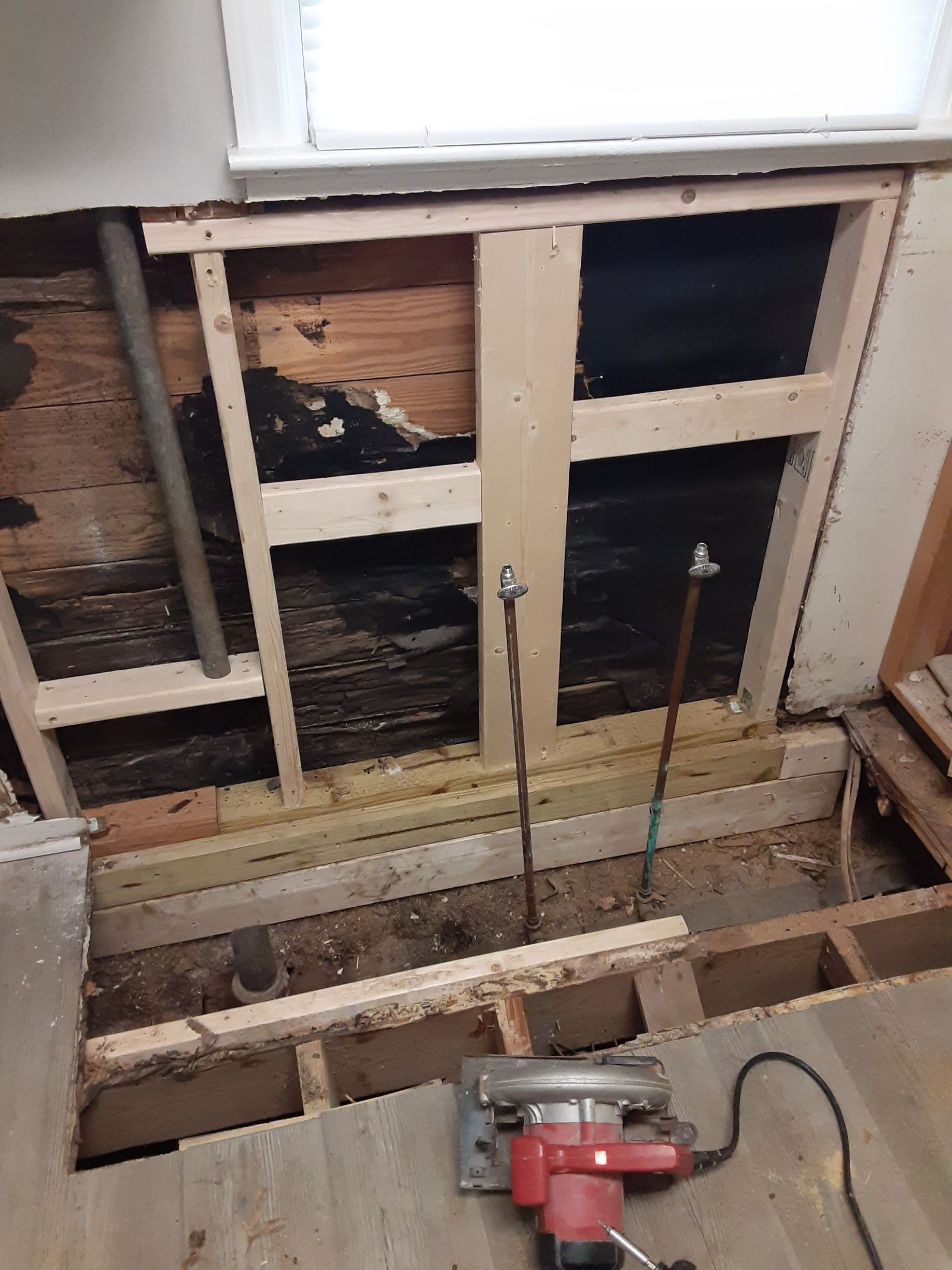A circular saw is sitting on the floor of a room under construction.