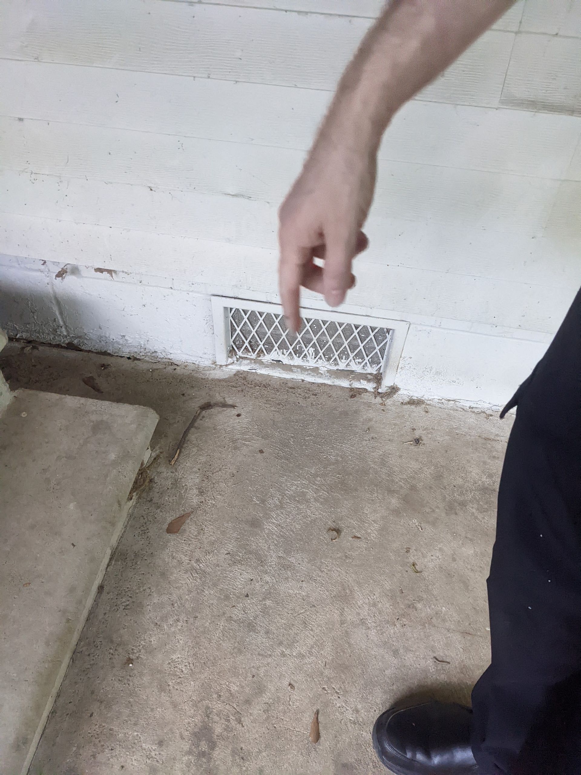 A person is pointing at a vent on the floor.