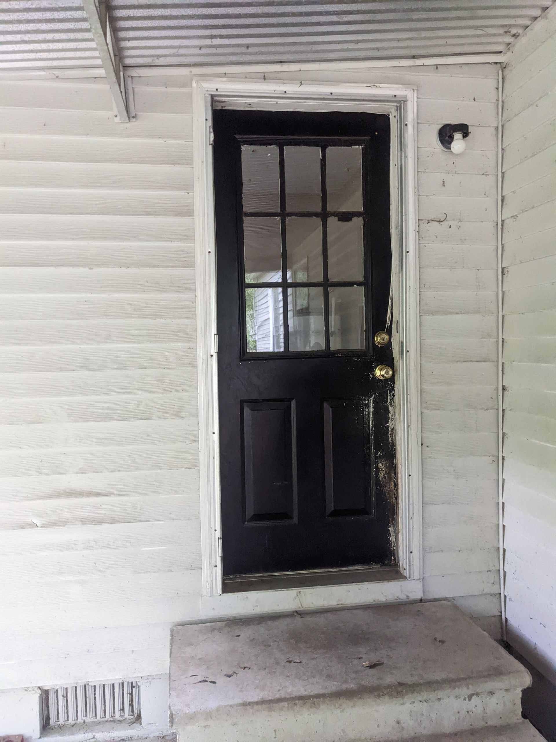 A black door with a glass window is on a white house