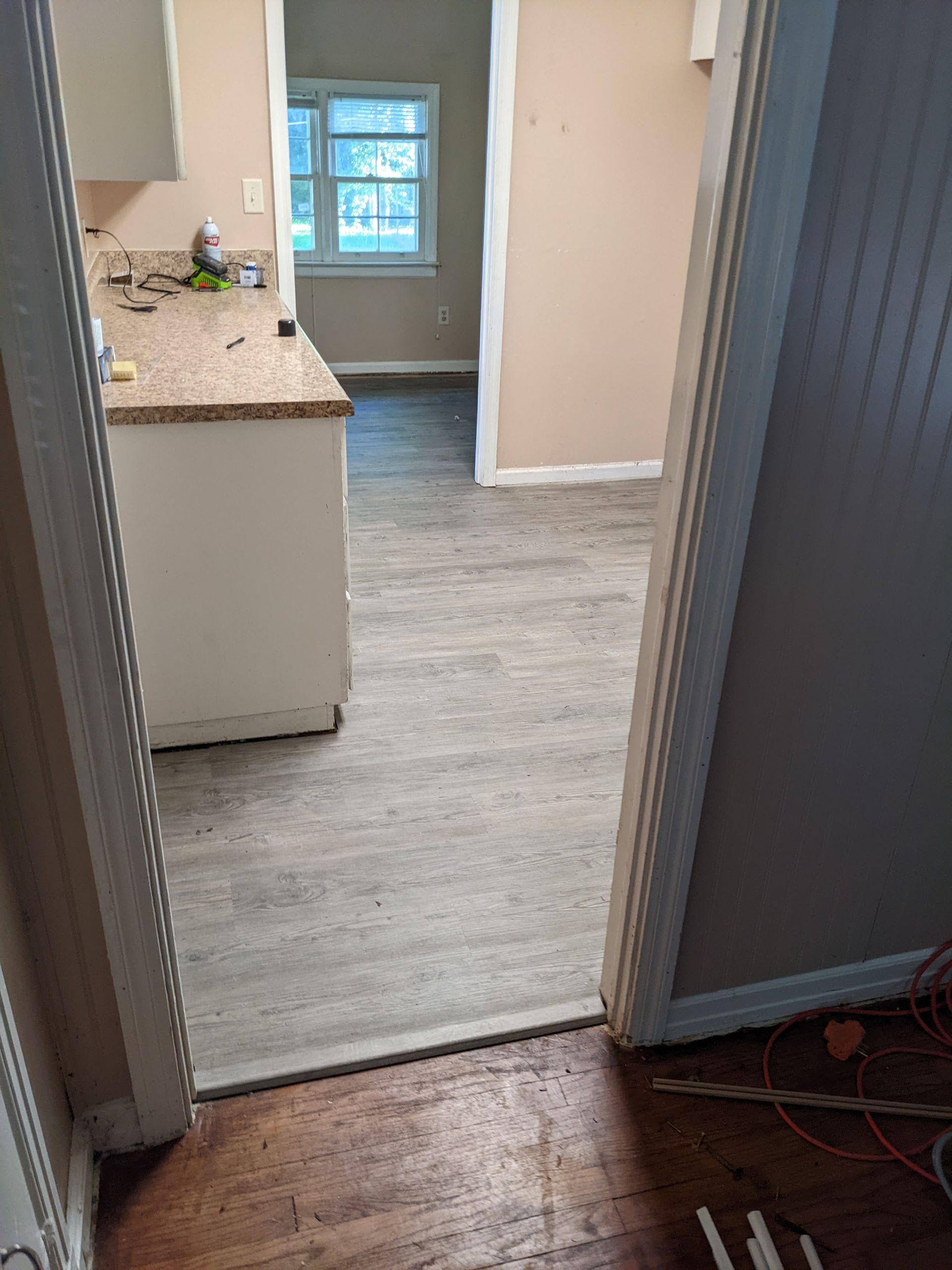 A doorway leading to a kitchen with a wooden floor and a window.