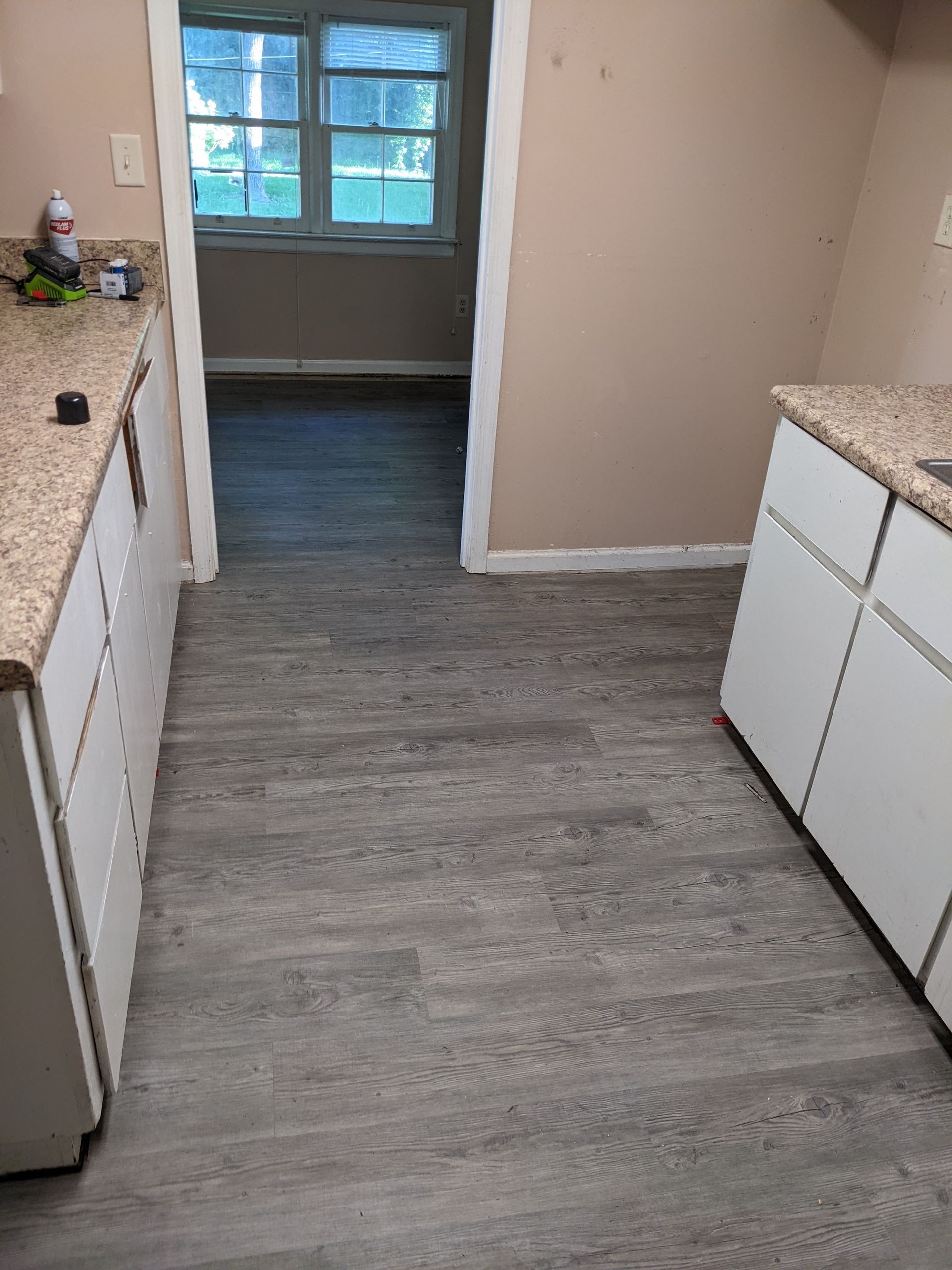 A kitchen with hardwood floors , granite counter tops , and white cabinets.