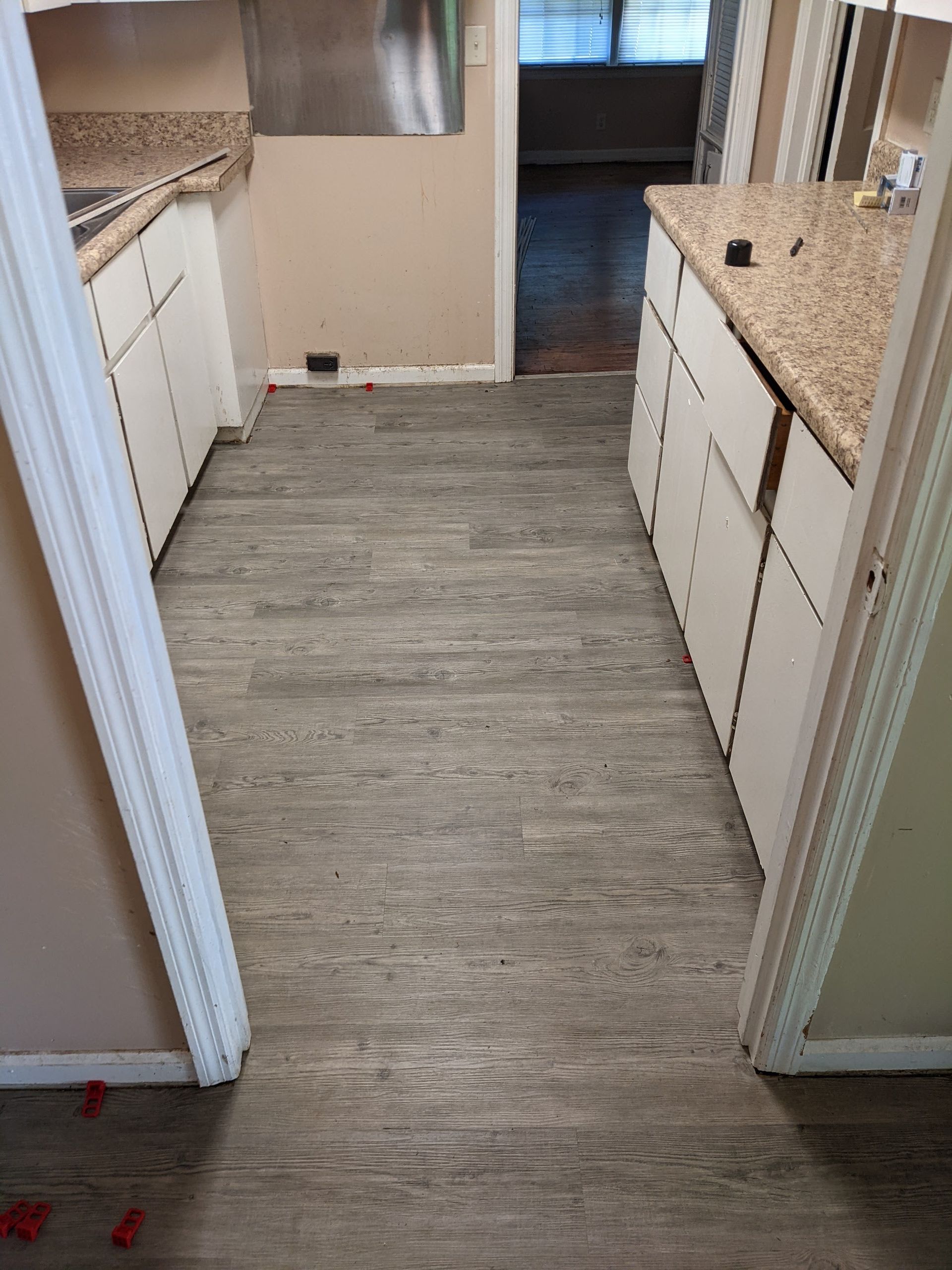 A kitchen with a wooden floor and white cabinets.