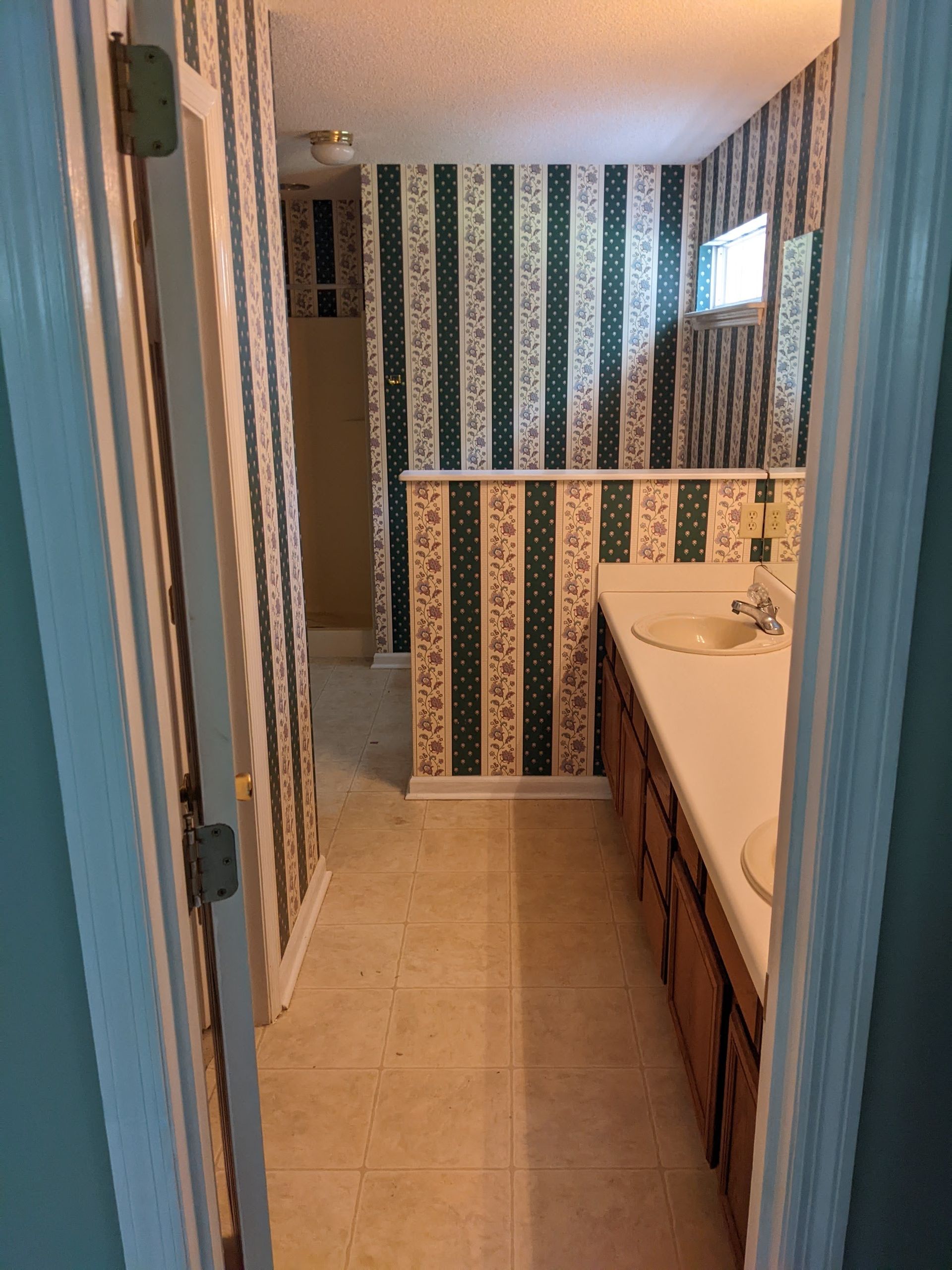 A bathroom with striped wallpaper and a sink and mirror