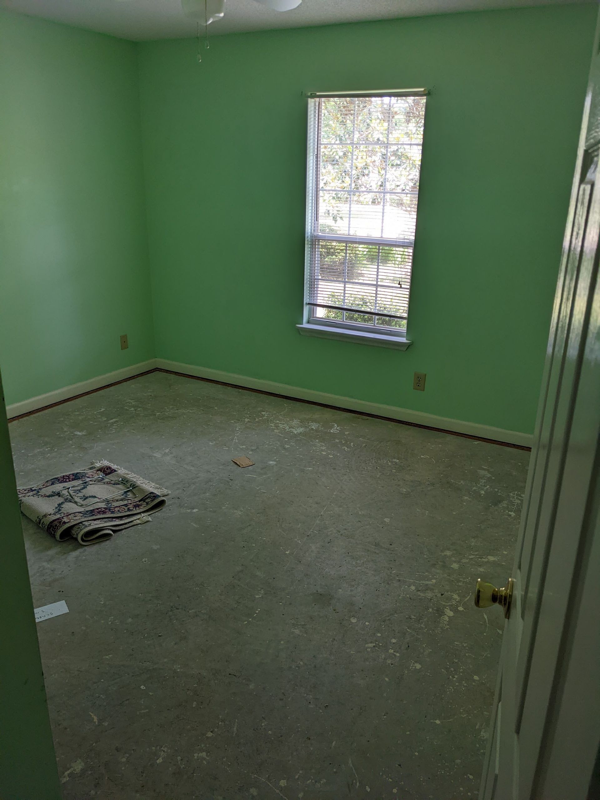 An empty room with green walls and a window.