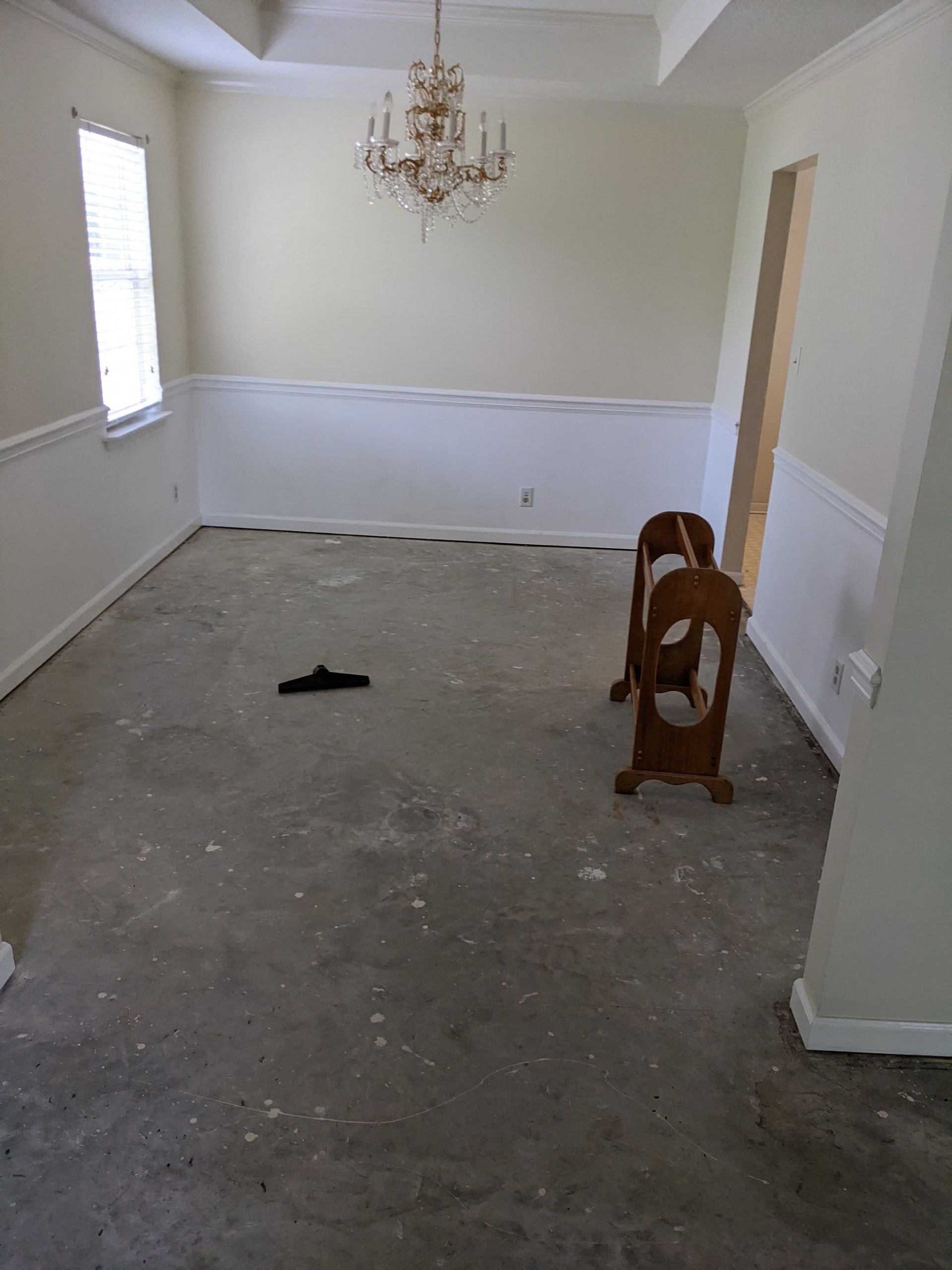An empty dining room with a chandelier hanging from the ceiling.